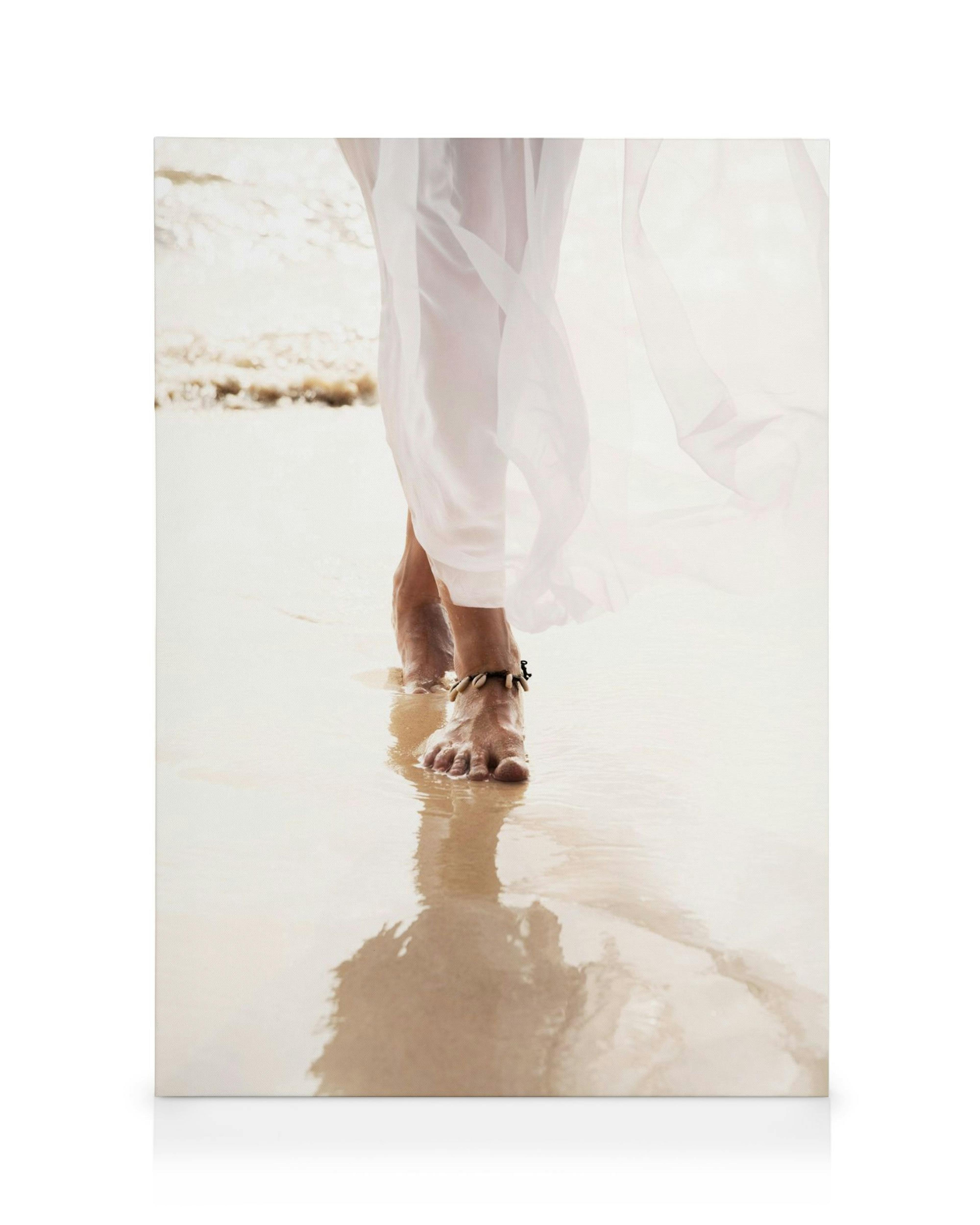 Føtter i hvit kjole går i våt sand på stranden, reflektert i vannet. Strand, sommer, beige, hvit.