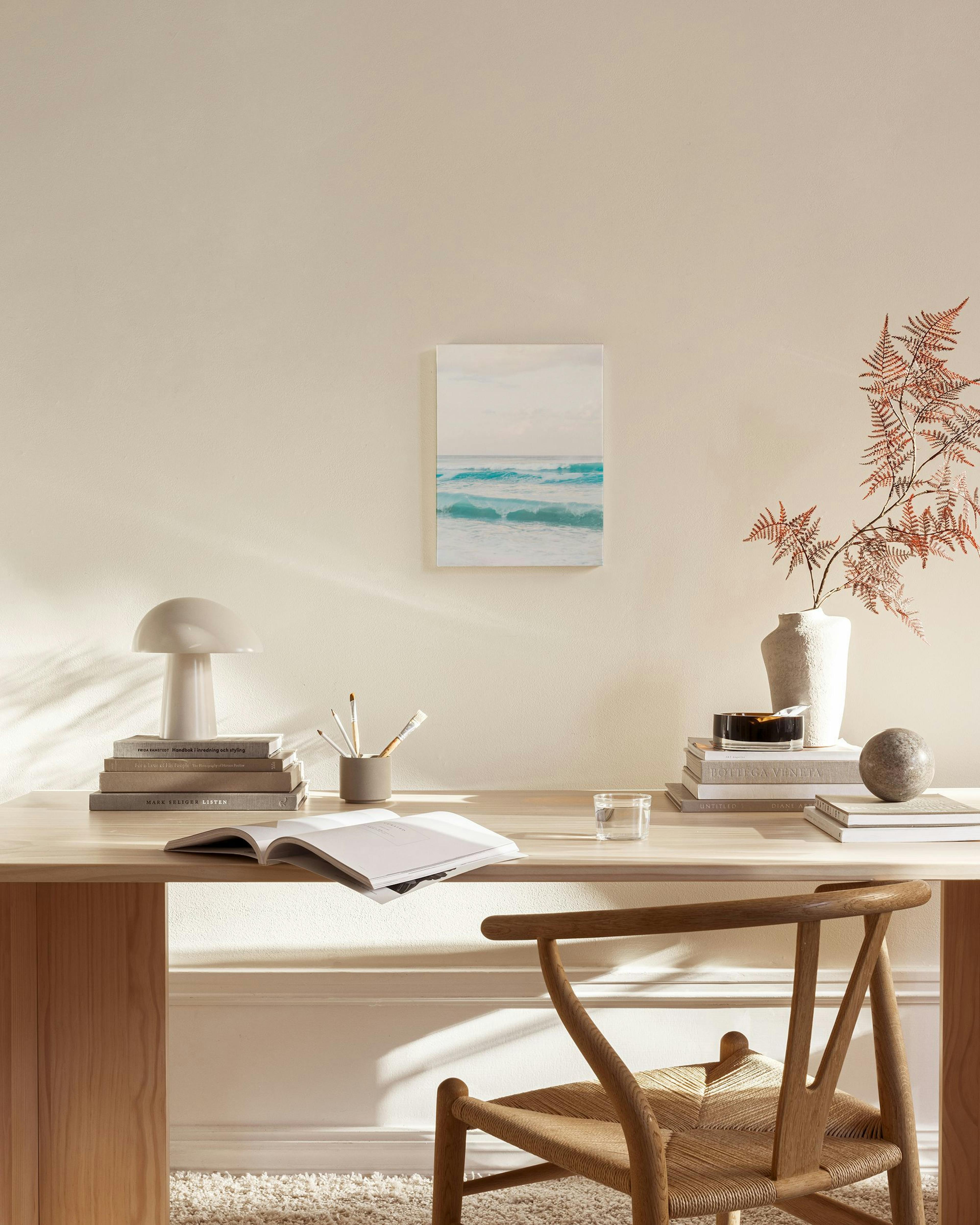 A canvas print of serene teal ocean waves under a soft sky, displayed in a bright, modern living room.