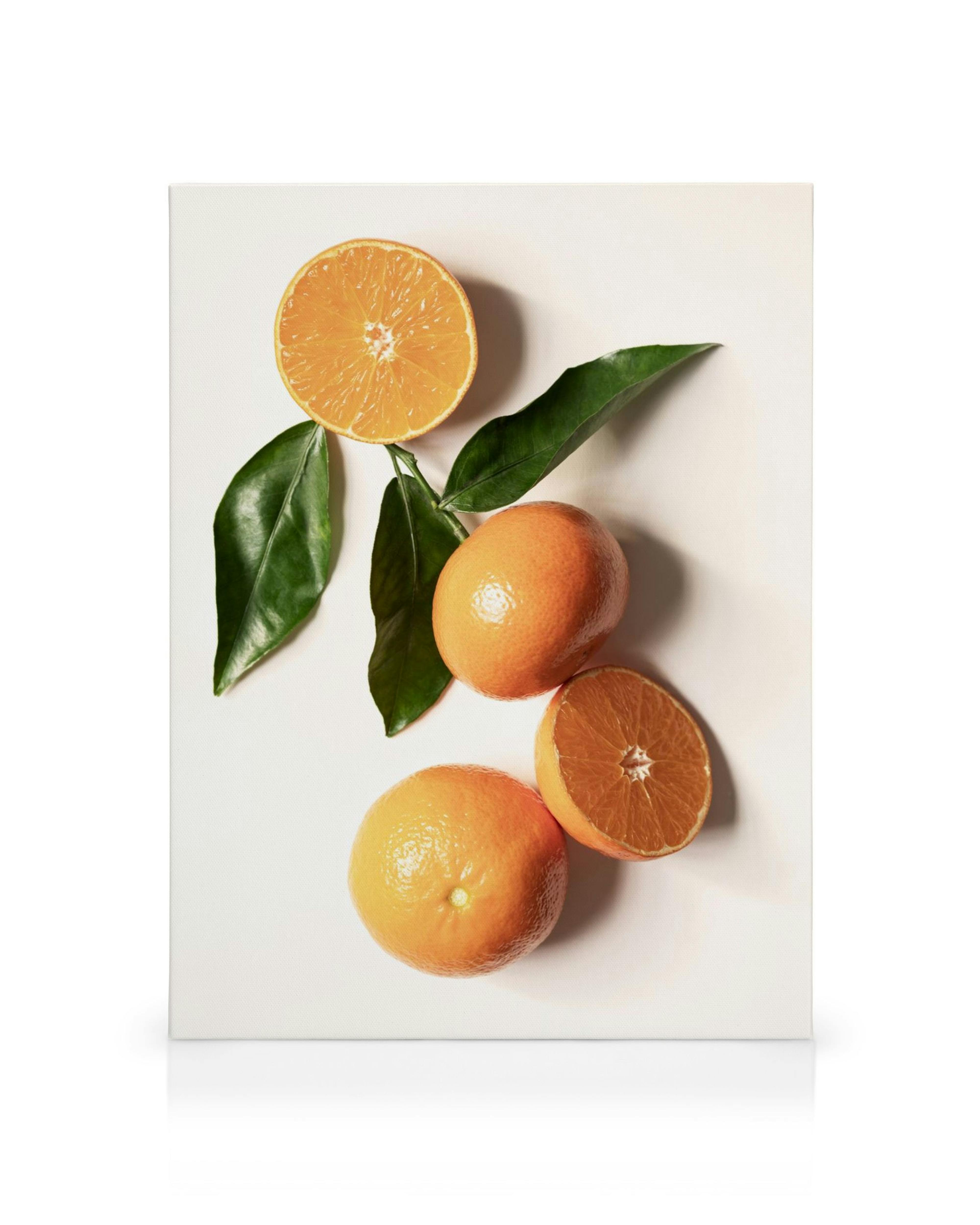 Livfulla apelsiner och gröna blad på en vit bakgrund, en perfekt canvastavla för köket.
