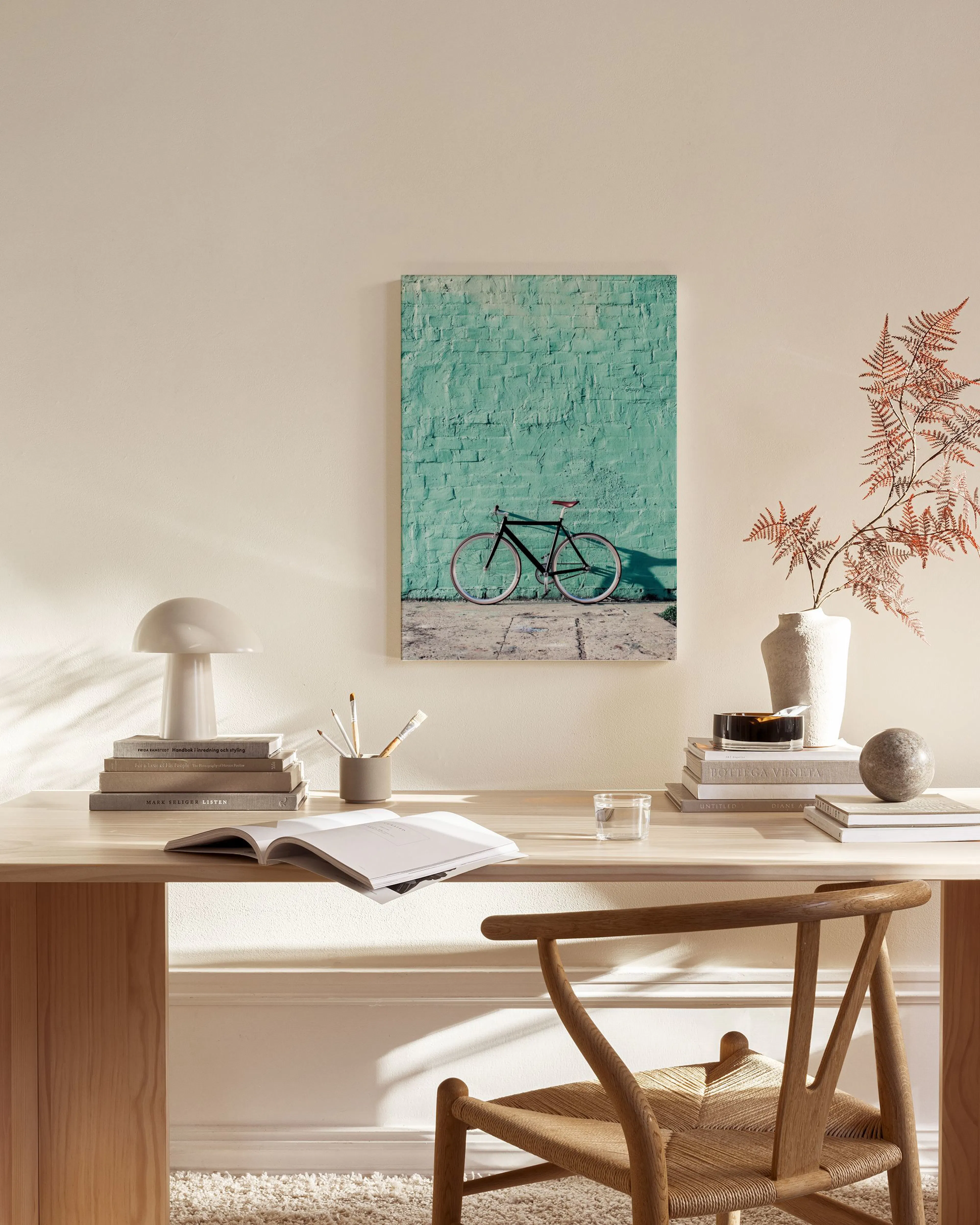 Toile dune bicyclette noire garée devant un mur vert turquoise, affichée dans un salon moderne.