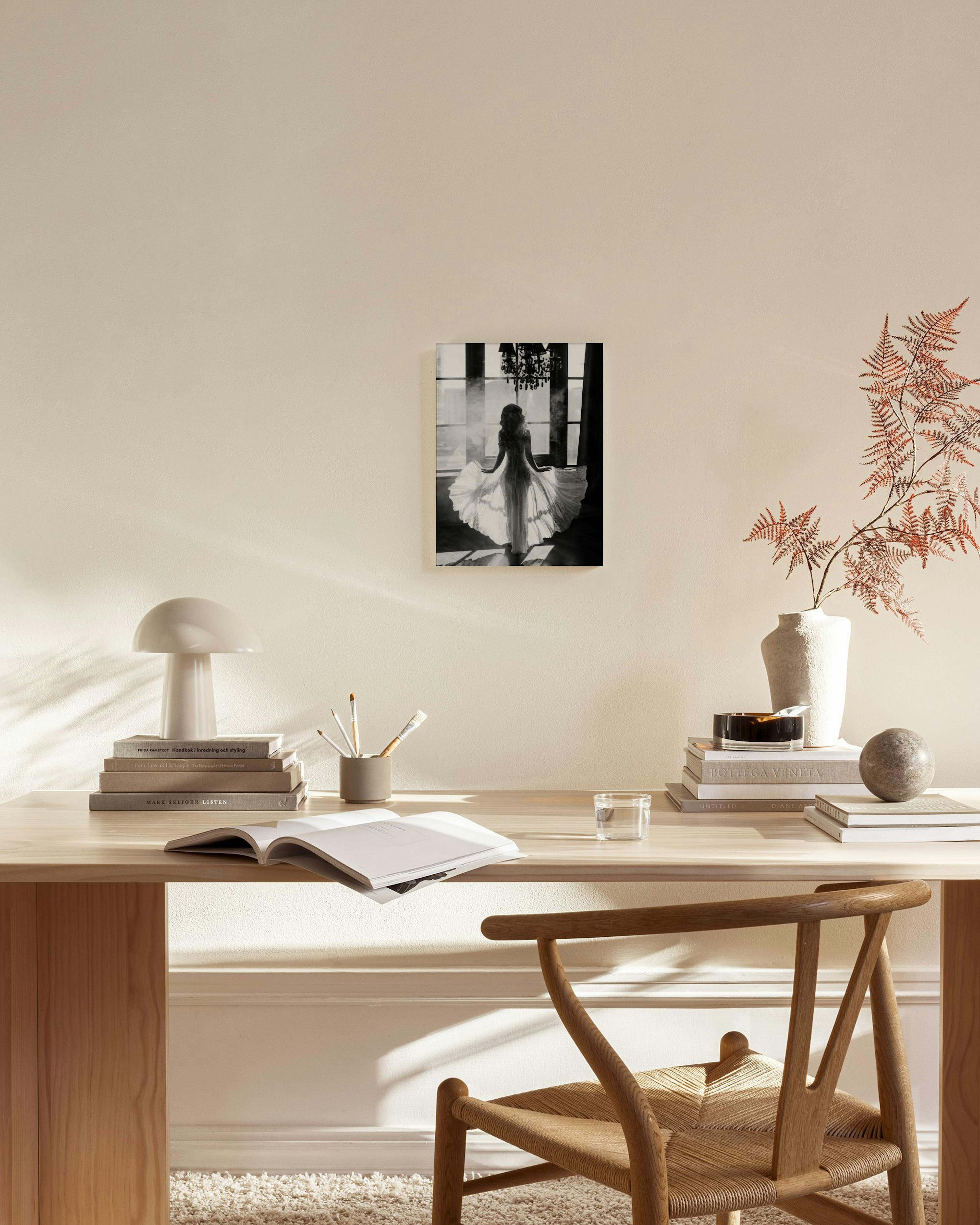 Black and white canvas print of a woman in a flowing dress, backlit by a window, displayed in a modern living room.