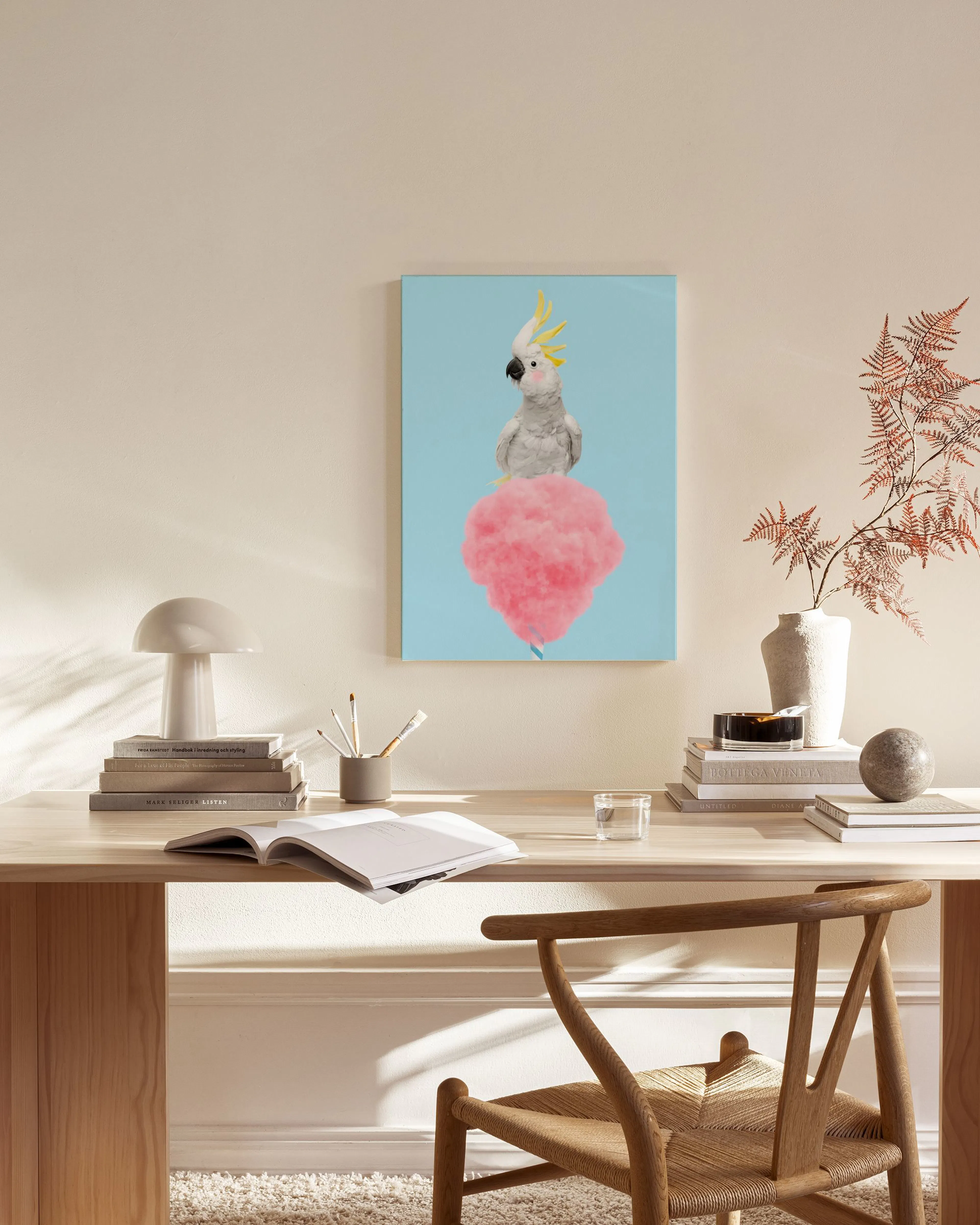 A cockatoo with yellow crest on pink cotton candy on a blue background, hanging in a minimalist living room.