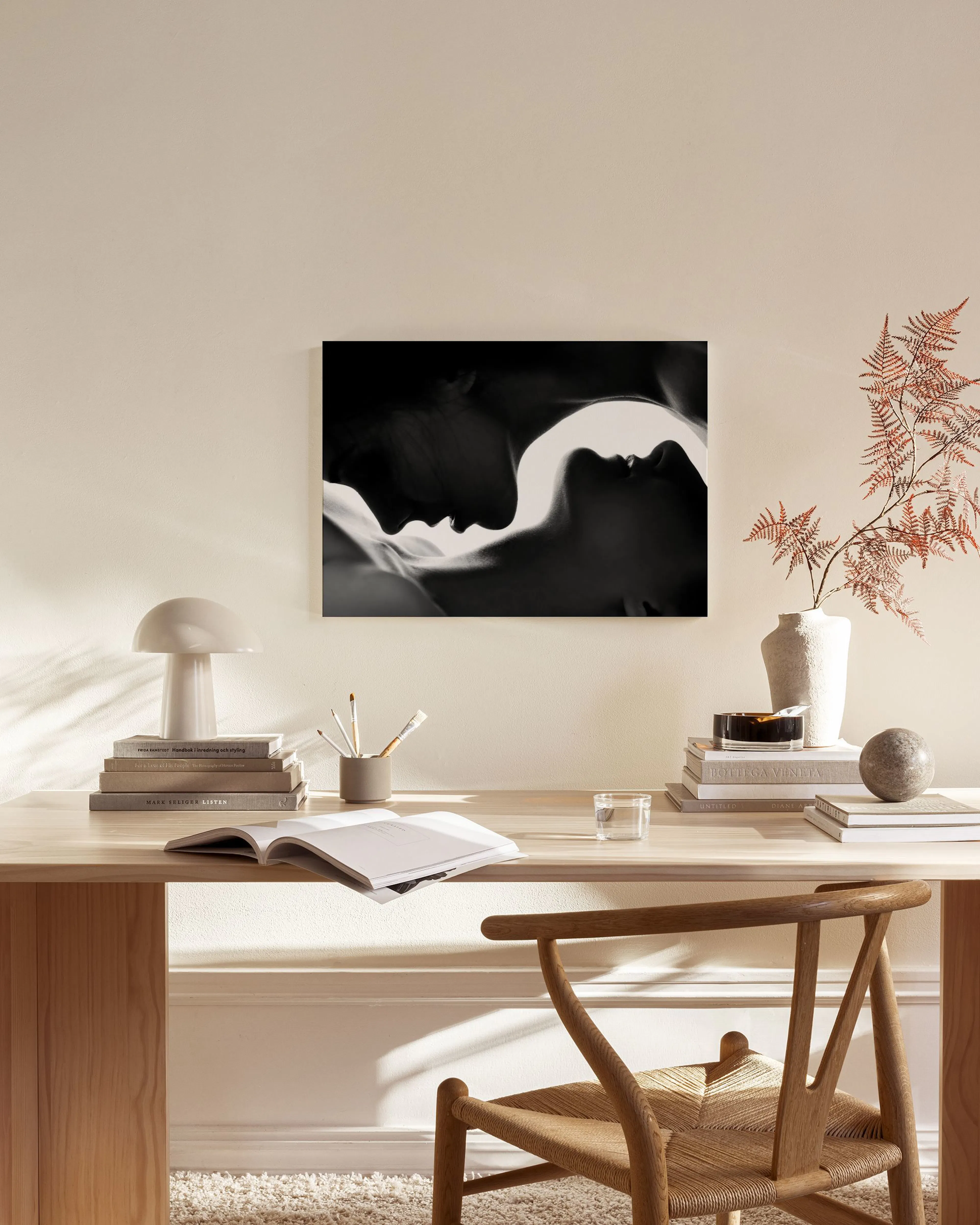 A black and white canvas print showing two faces in profile, almost touching, hanging above a console table in a minimalist livi