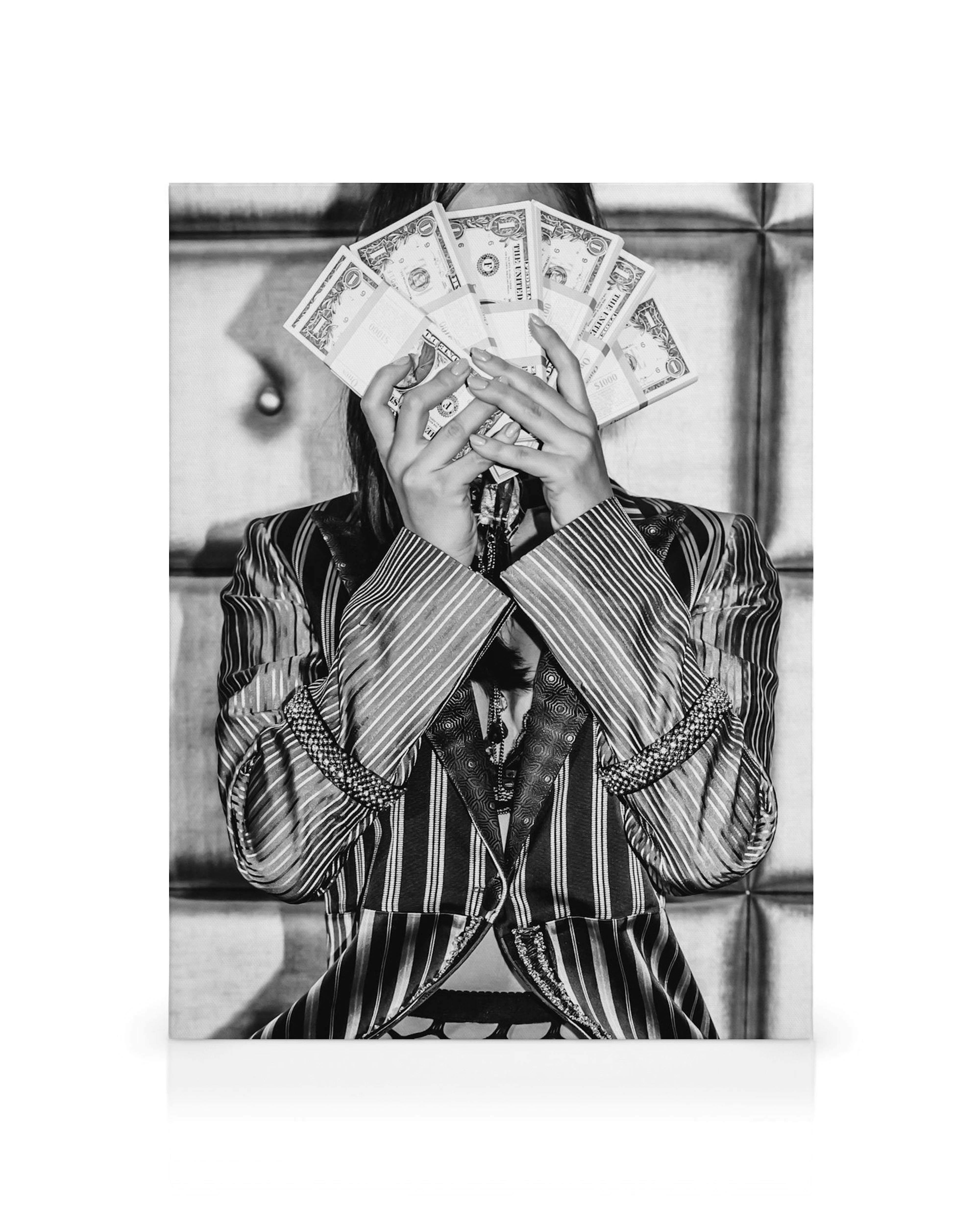 Toile en noir et blanc: personne en veste rayée tenant de largent devant son visage, arrière-plan géométrique.