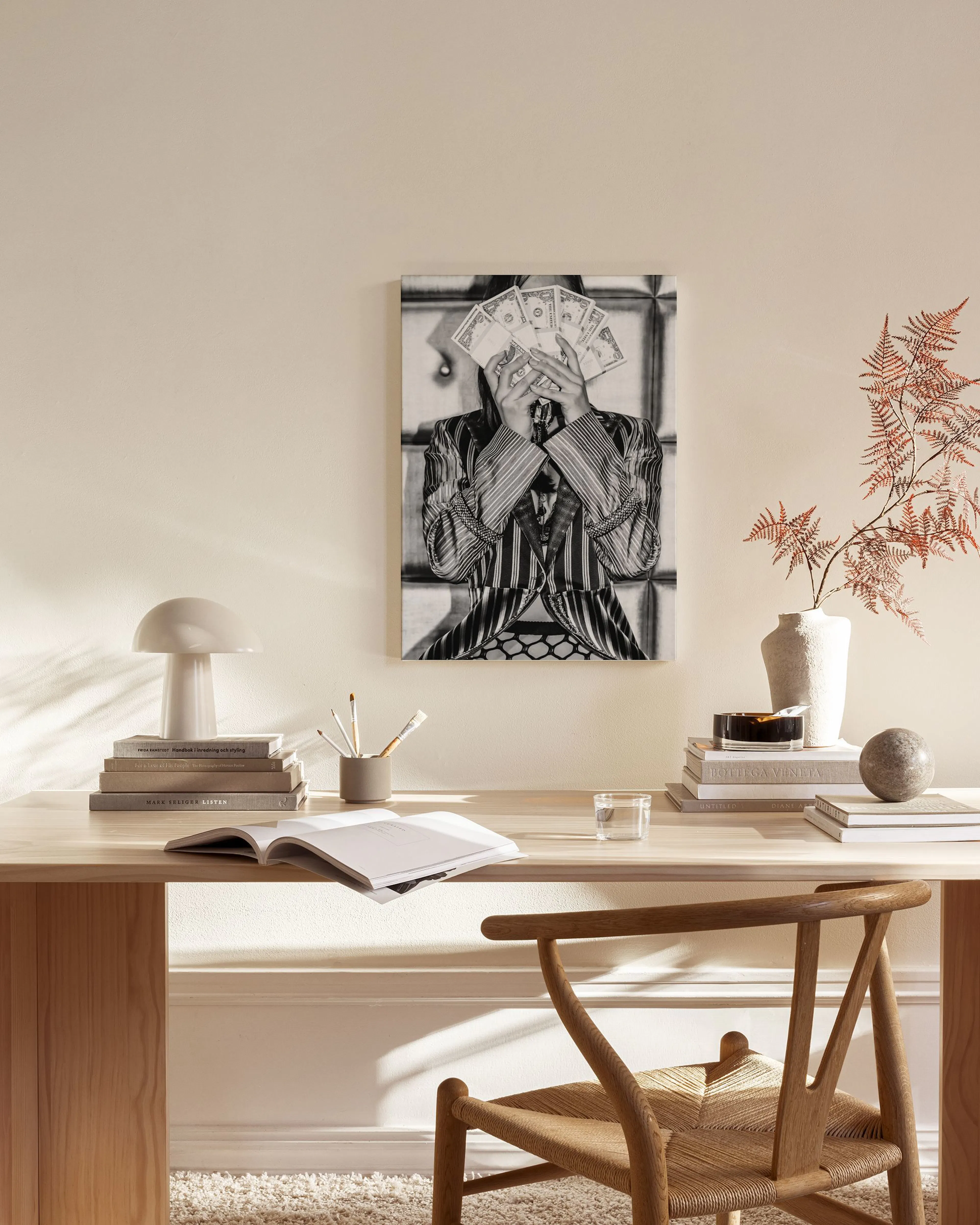 Black and white canvas print of a person holding money to their face, displayed in a modern living room above a wooden console t