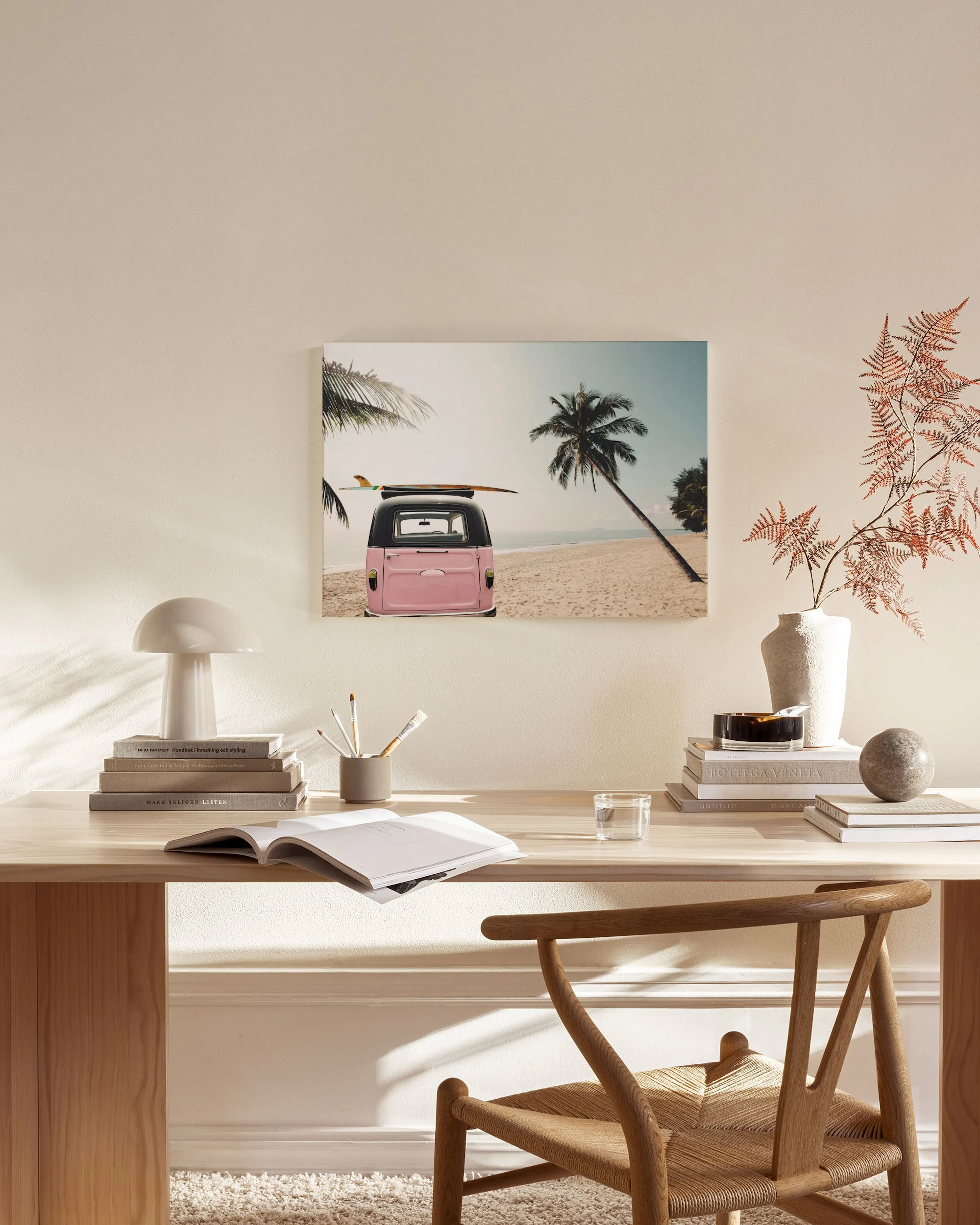 Canvas van een roze Volkswagenbusje met surfplank op een zandstrand tussen palmbomen, hangend in een moderne woonkamer.