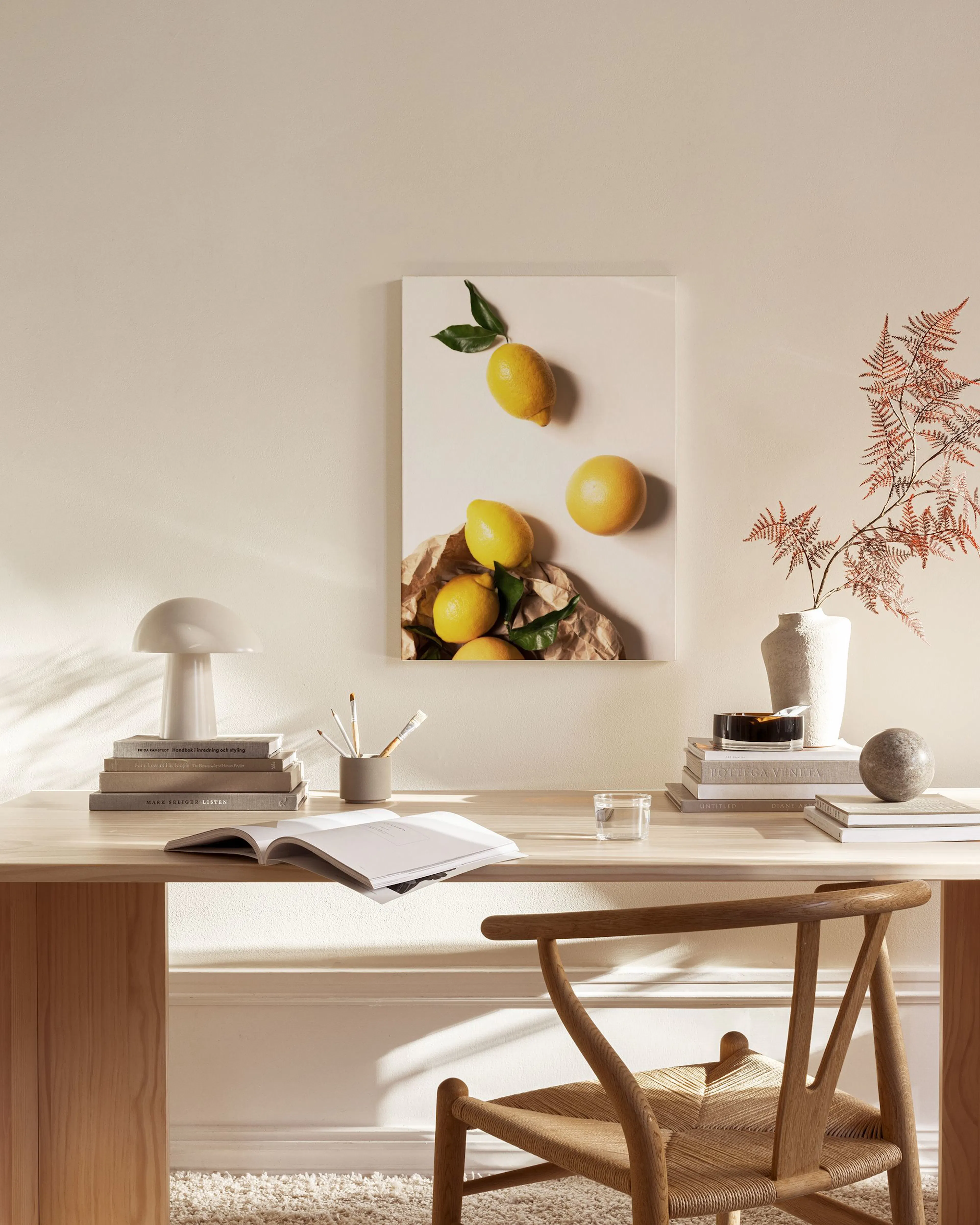 Leinwandbild mit Zitronen auf Packpapier, hängend in einem hellen Wohnzimmer über einem Sideboard.