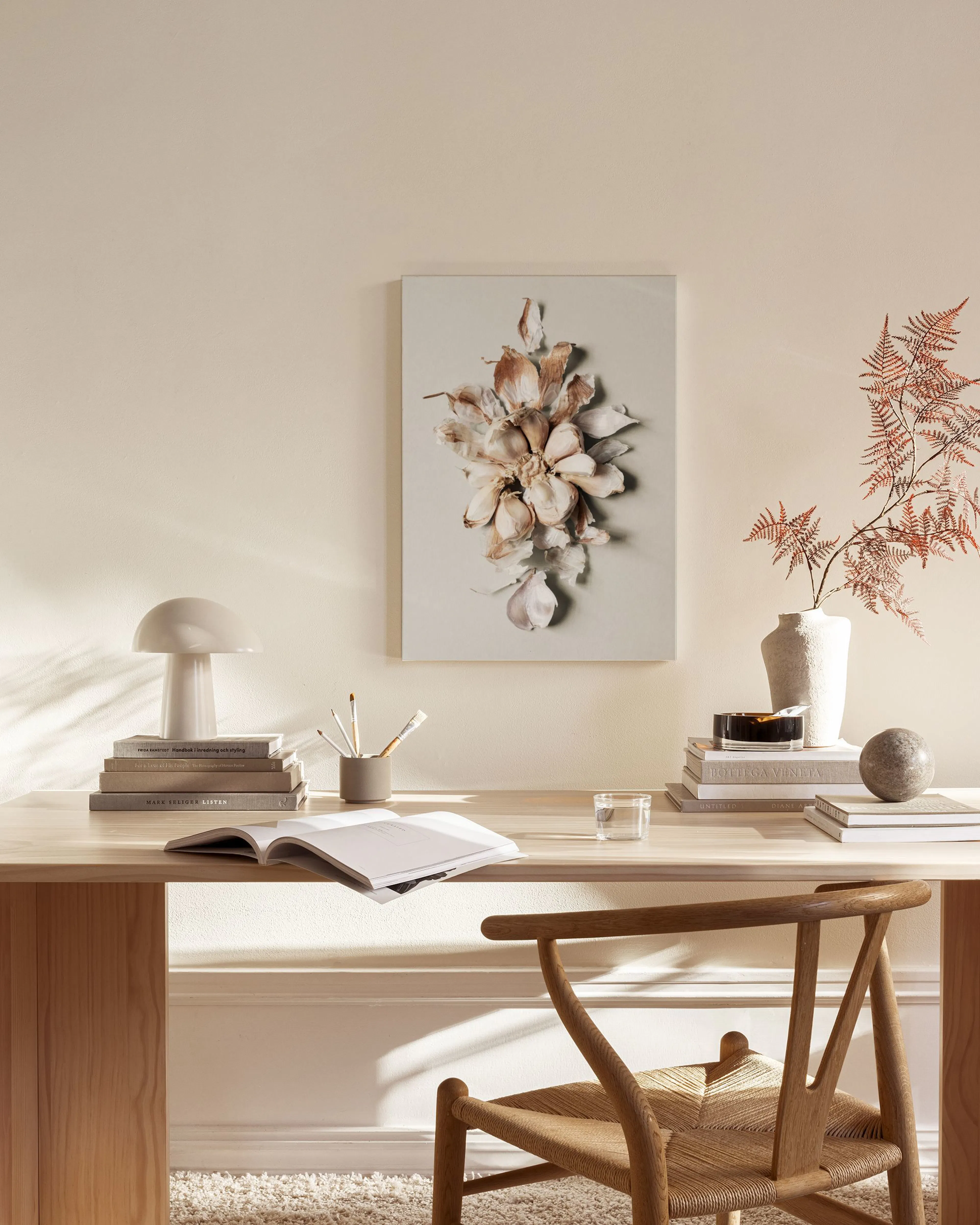 Canvas van gedroogde bloemen in beige-bruine tinten, hangend in een neutrale woonkamer met houten meubels.