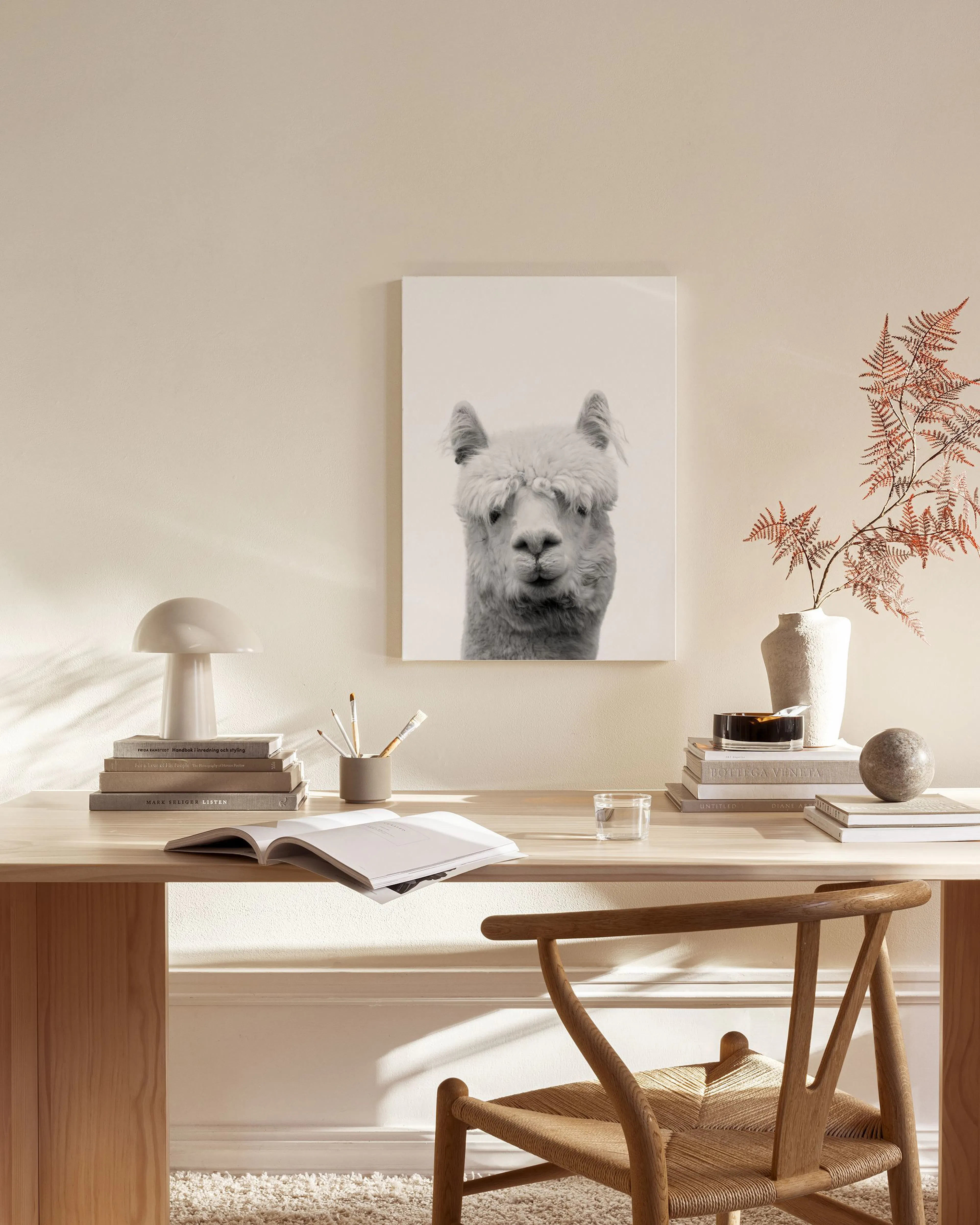 Canvas met zwart-wit foto van een alpaca die recht aankijkt, hangend in een neutrale woonkamer.