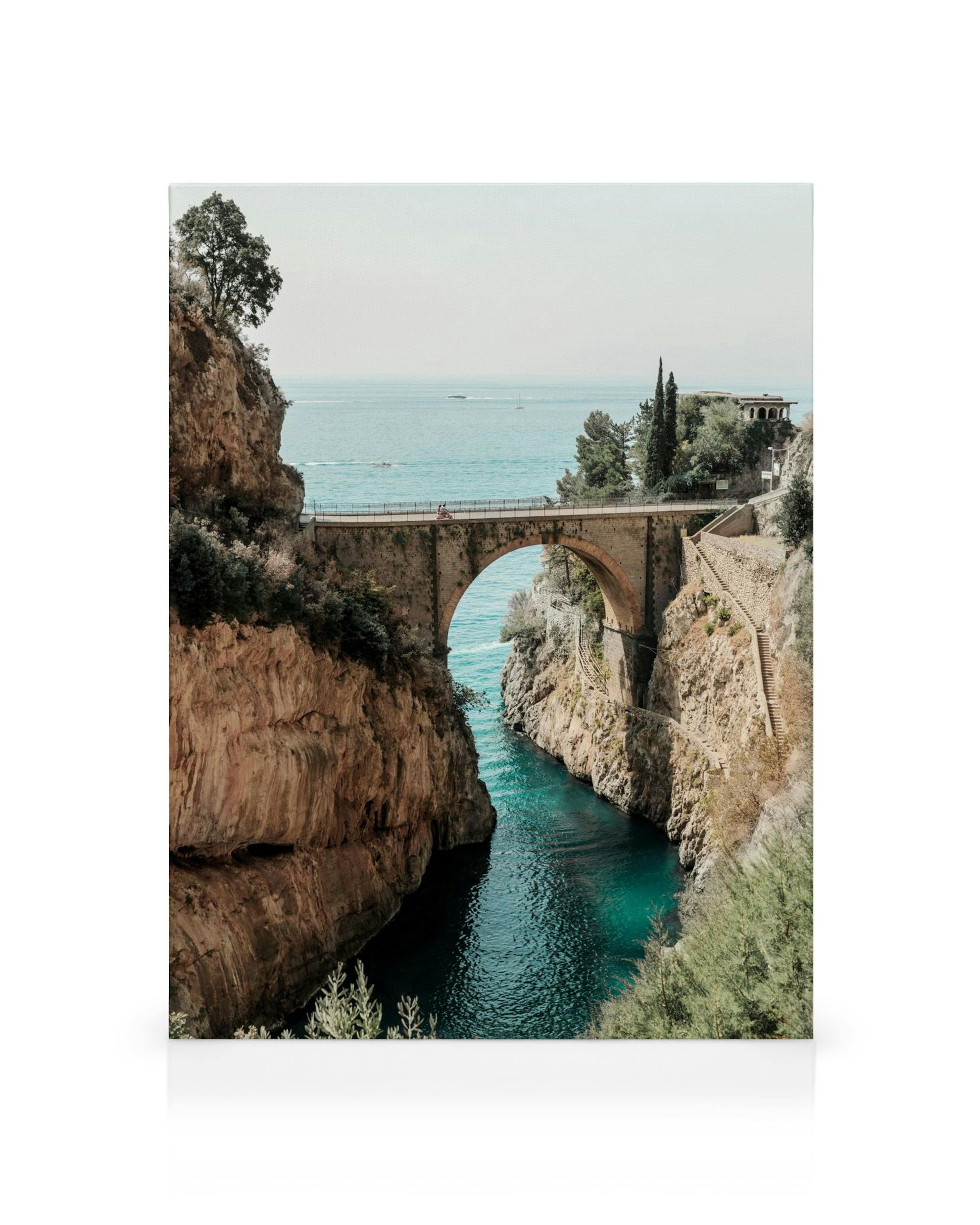 Fiordo di Furore canvas print featuring an old stone bridge over a narrow, turquoise waterway between rocky cliffs.
