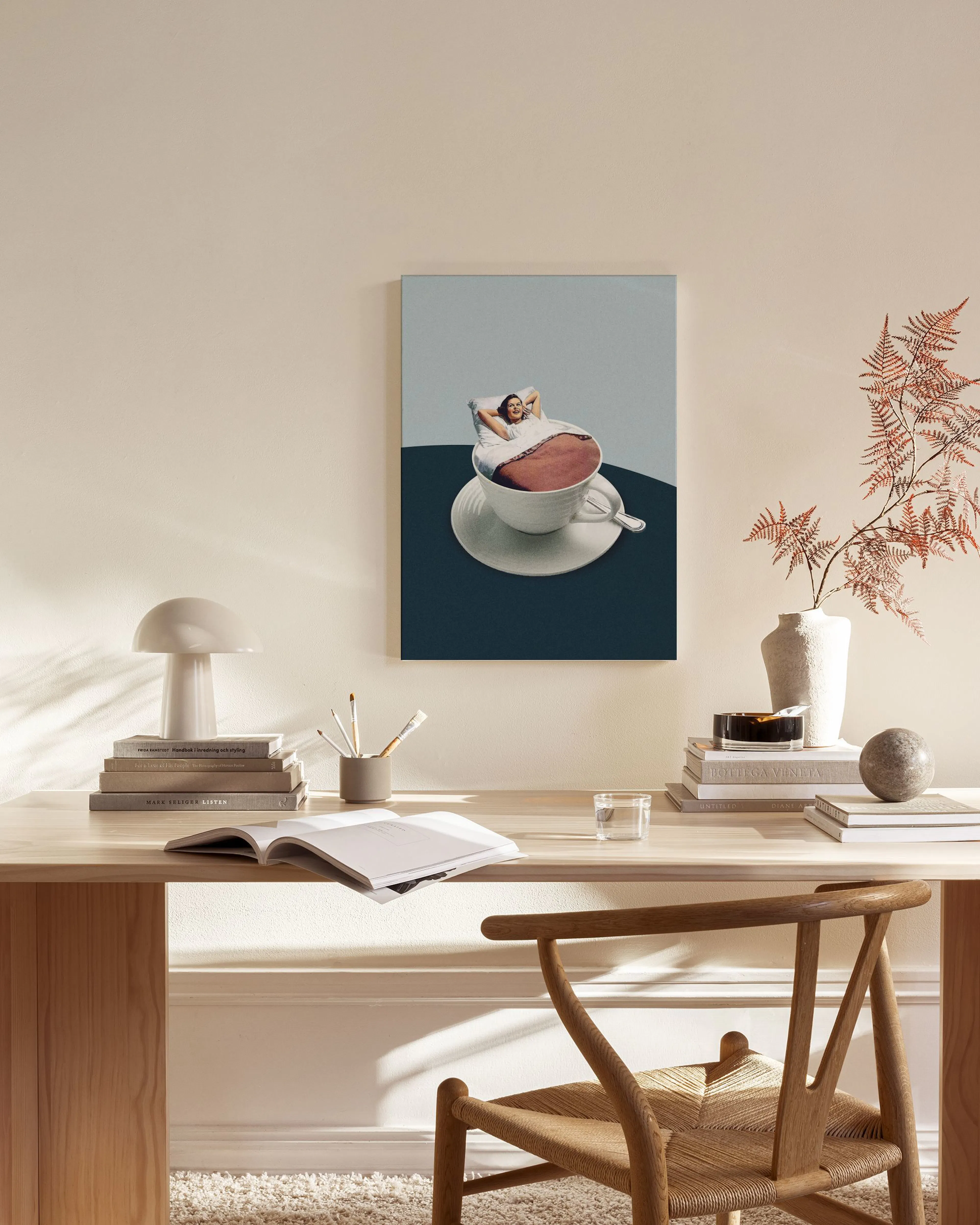 Canvas met collage van een vrouw die in een koffiekopje ligt, hangend in een neutrale woonkamer.