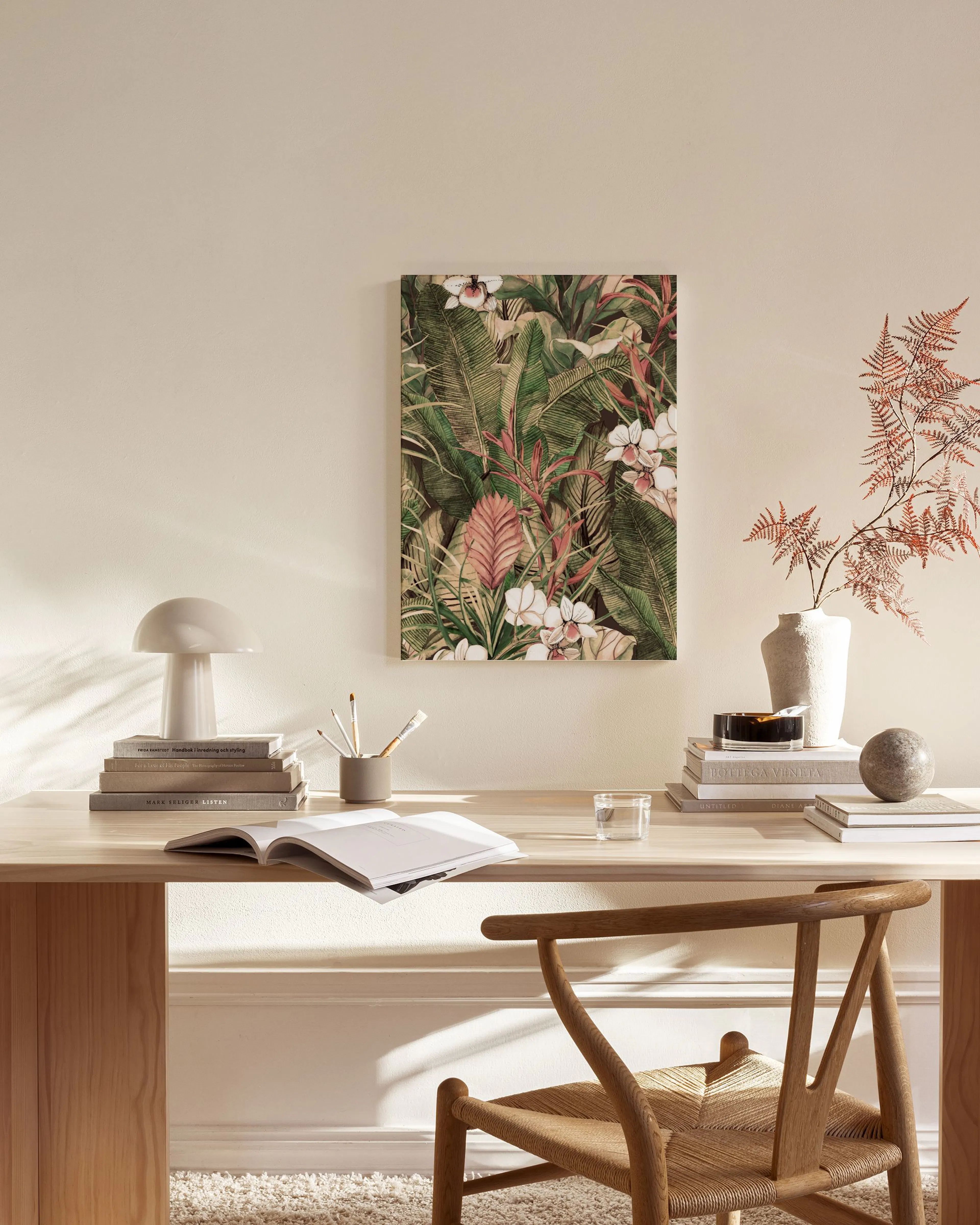 Canvastavla med exotiska gröna blad och vita blommor, hängandes i ett modernt vardagsrum med trädetaljer.
