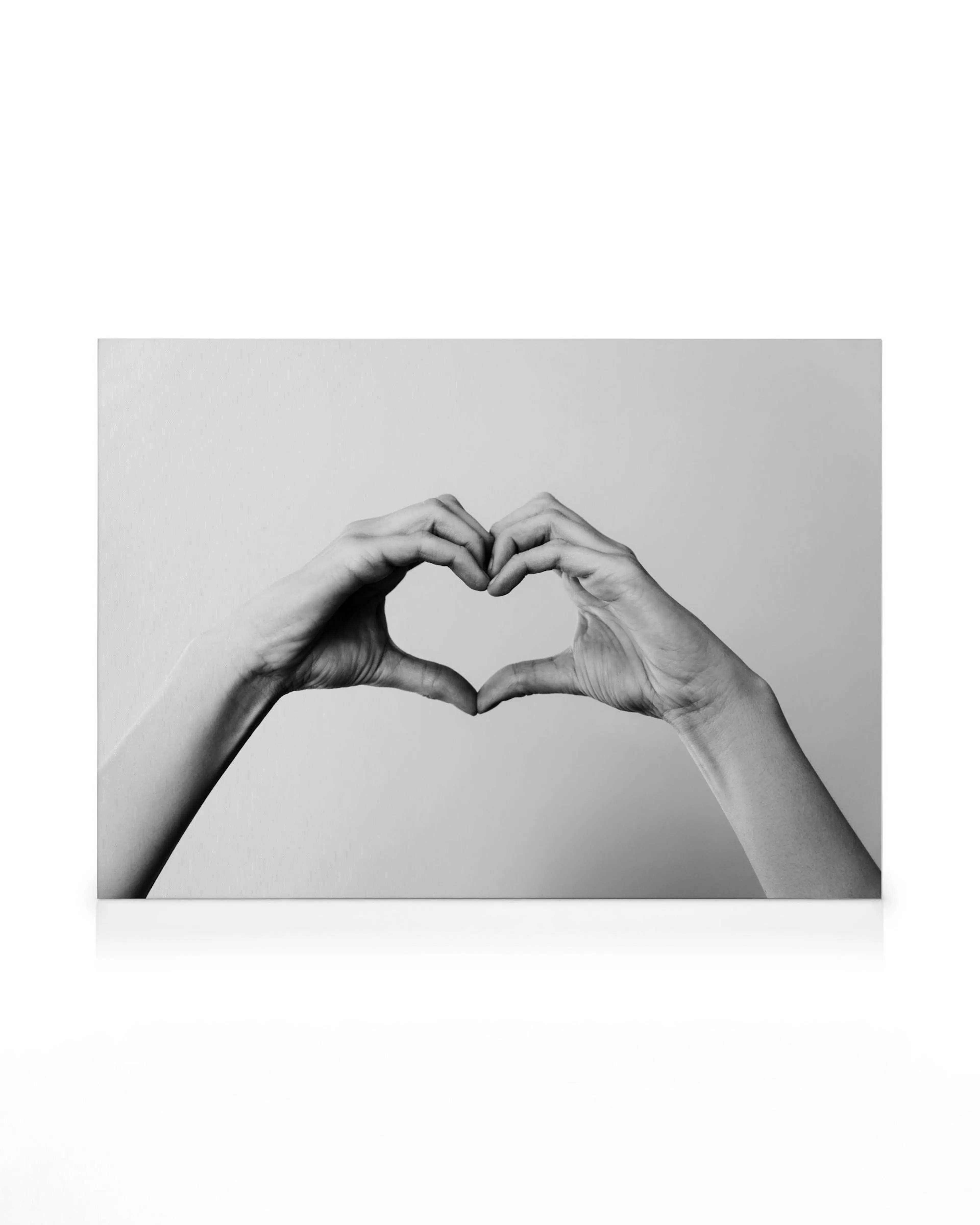 Leinwandbild mit Händen, die ein Herz formen, in Schwarz-Weiß, symbolisiert Liebe und Verbindung.