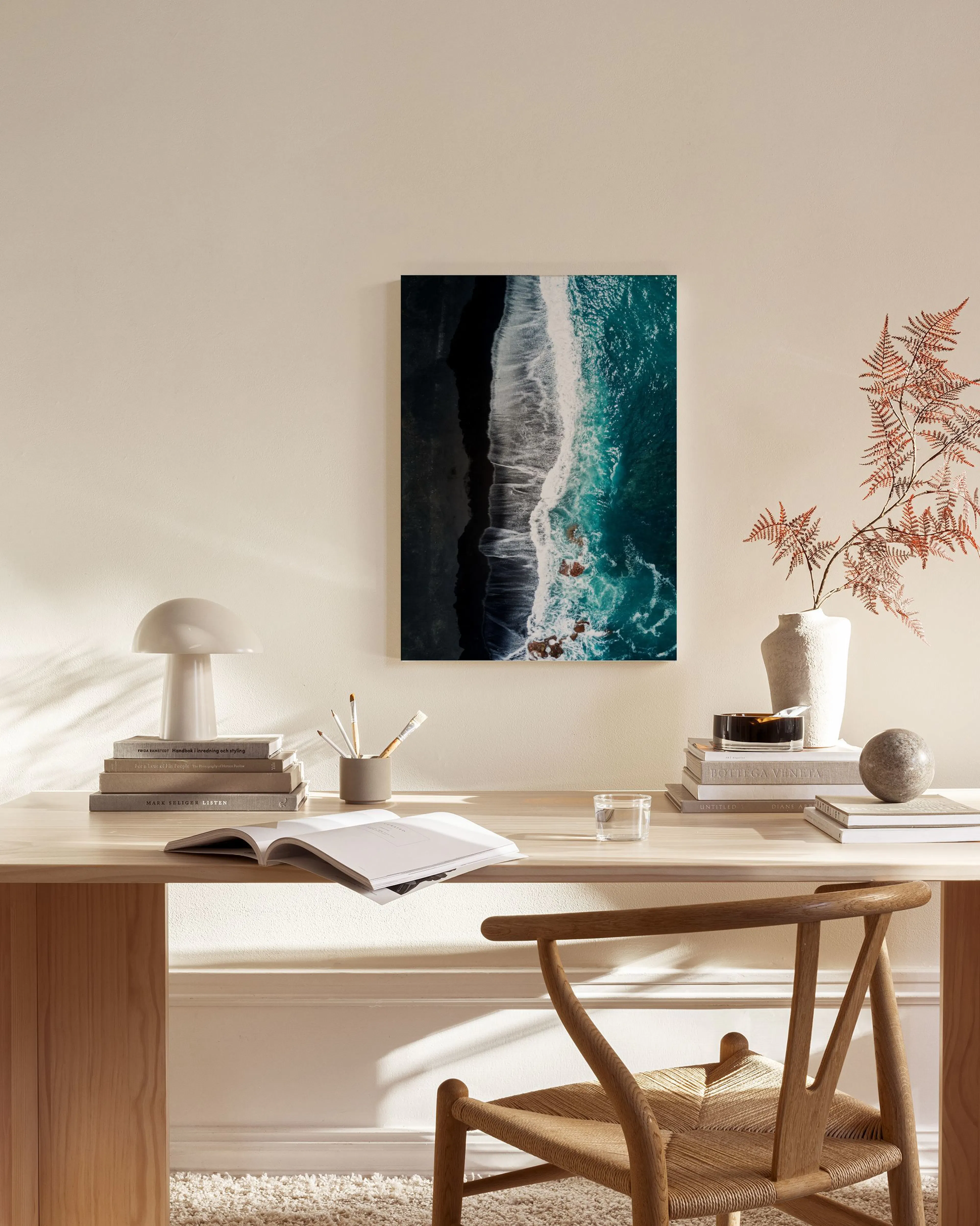 Leinwandbild einer Luftaufnahme von Wellen am schwarzen Sandstrand, hängend über einem Sideboard im Wohnzimmer.