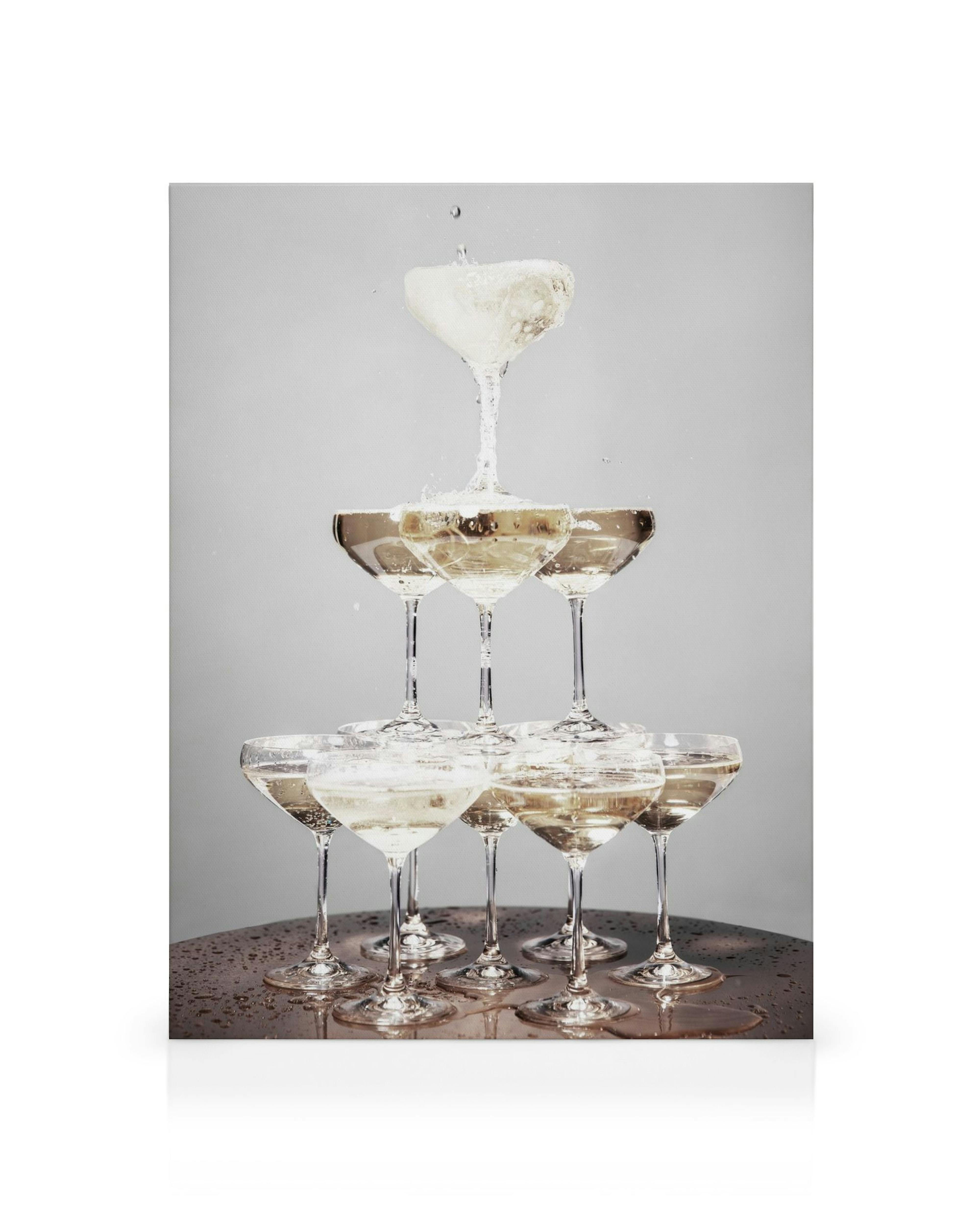 Champagneglasspyramide fylt med gyllen drikke, søl på bordet, grå bakgrunn. Elegante bobler.