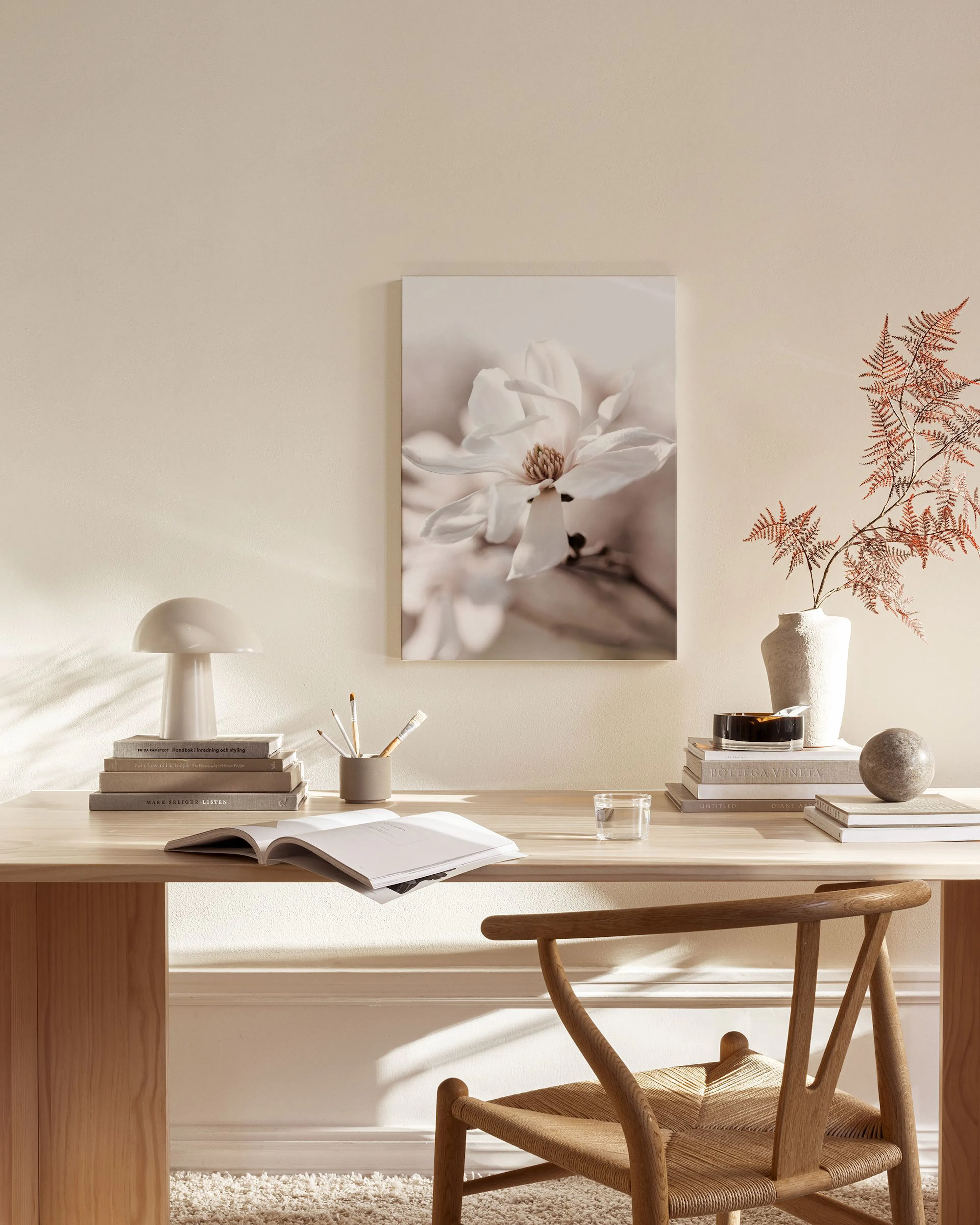 Canvastavla med en närbild av en vit magnolia, hängandes i ett ljust vardagsrum med trädetaljer.