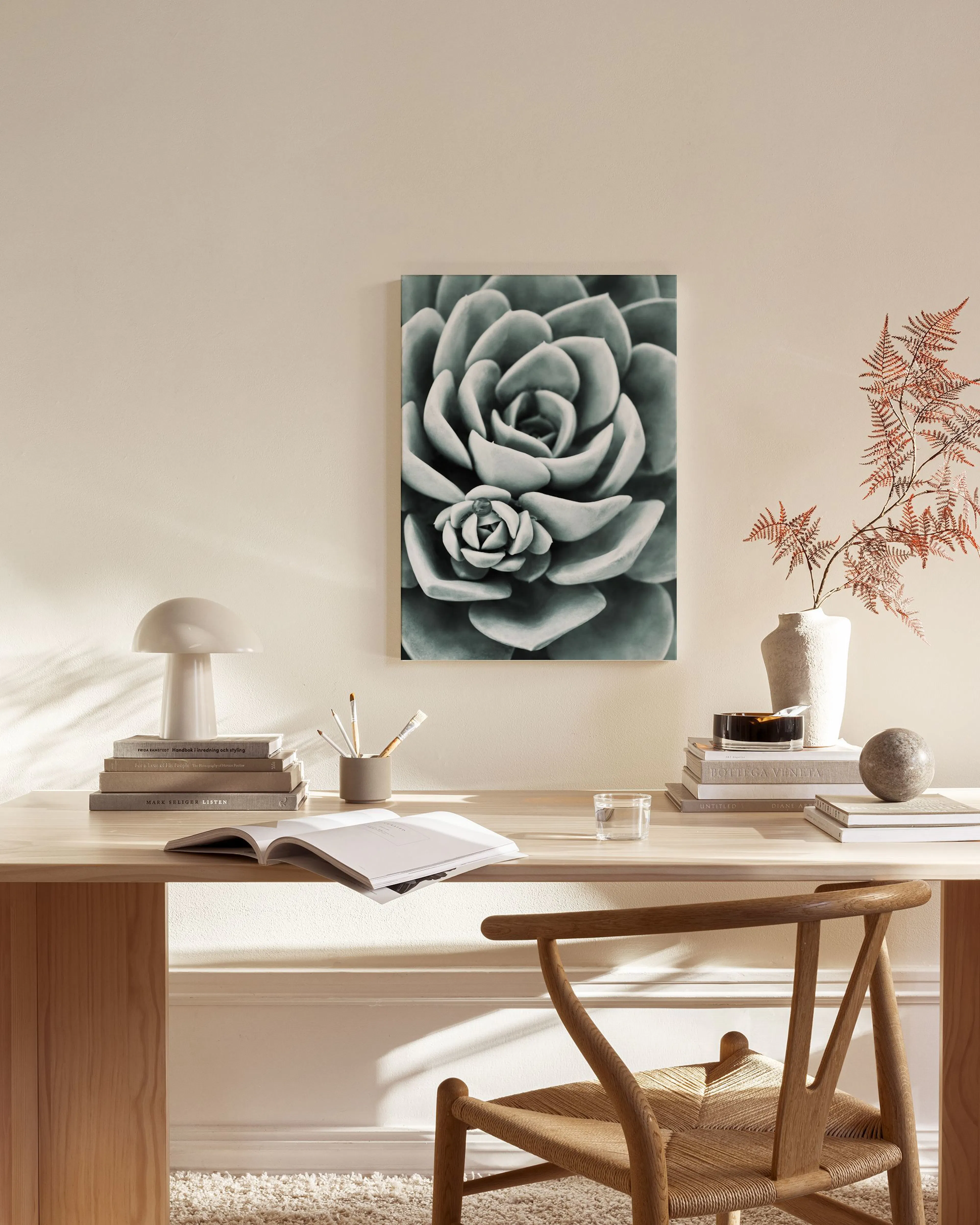 A canvas print of a green succulent with detailed rosettes, hanging on a light wall in a minimalist living room.