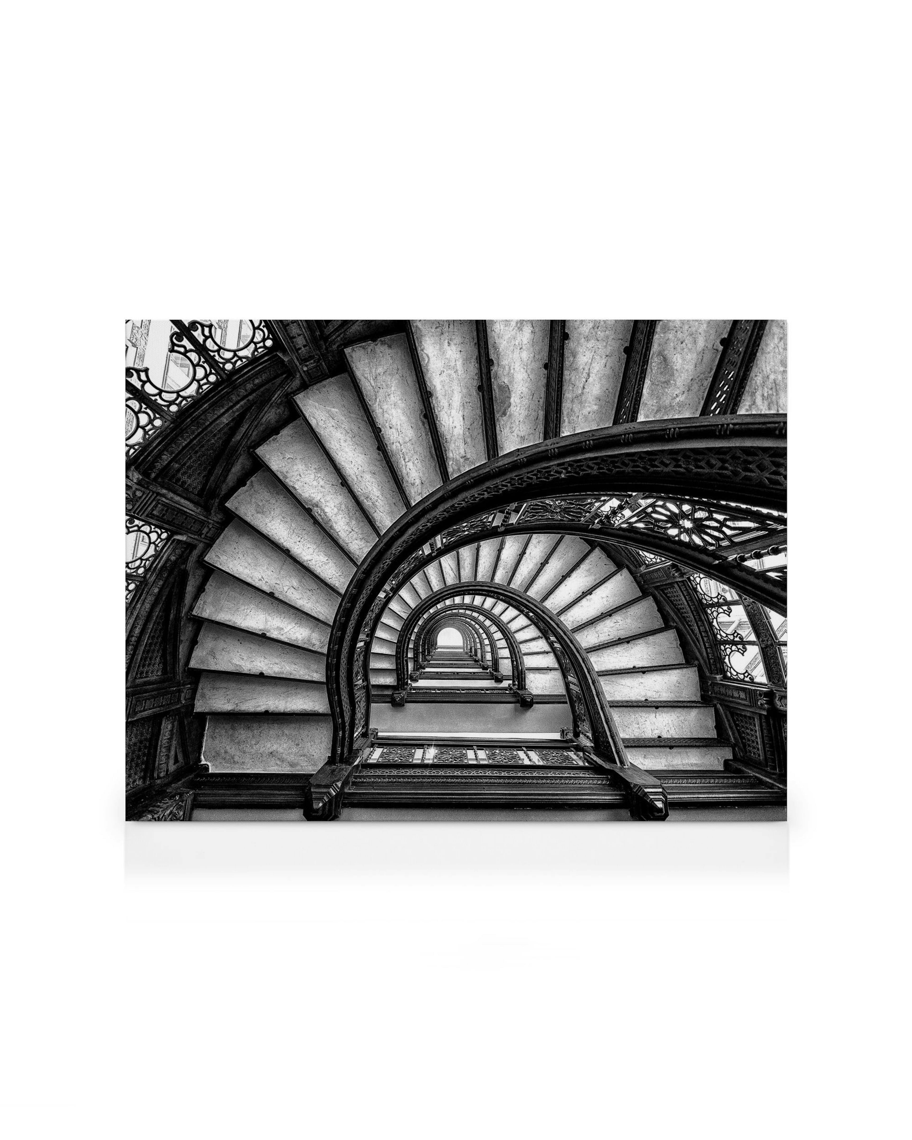 Schwarz-weißes Leinwandbild einer antiken, spiralförmigen Wendeltreppe aus der Vogelperspektive, die sich nach oben windet.