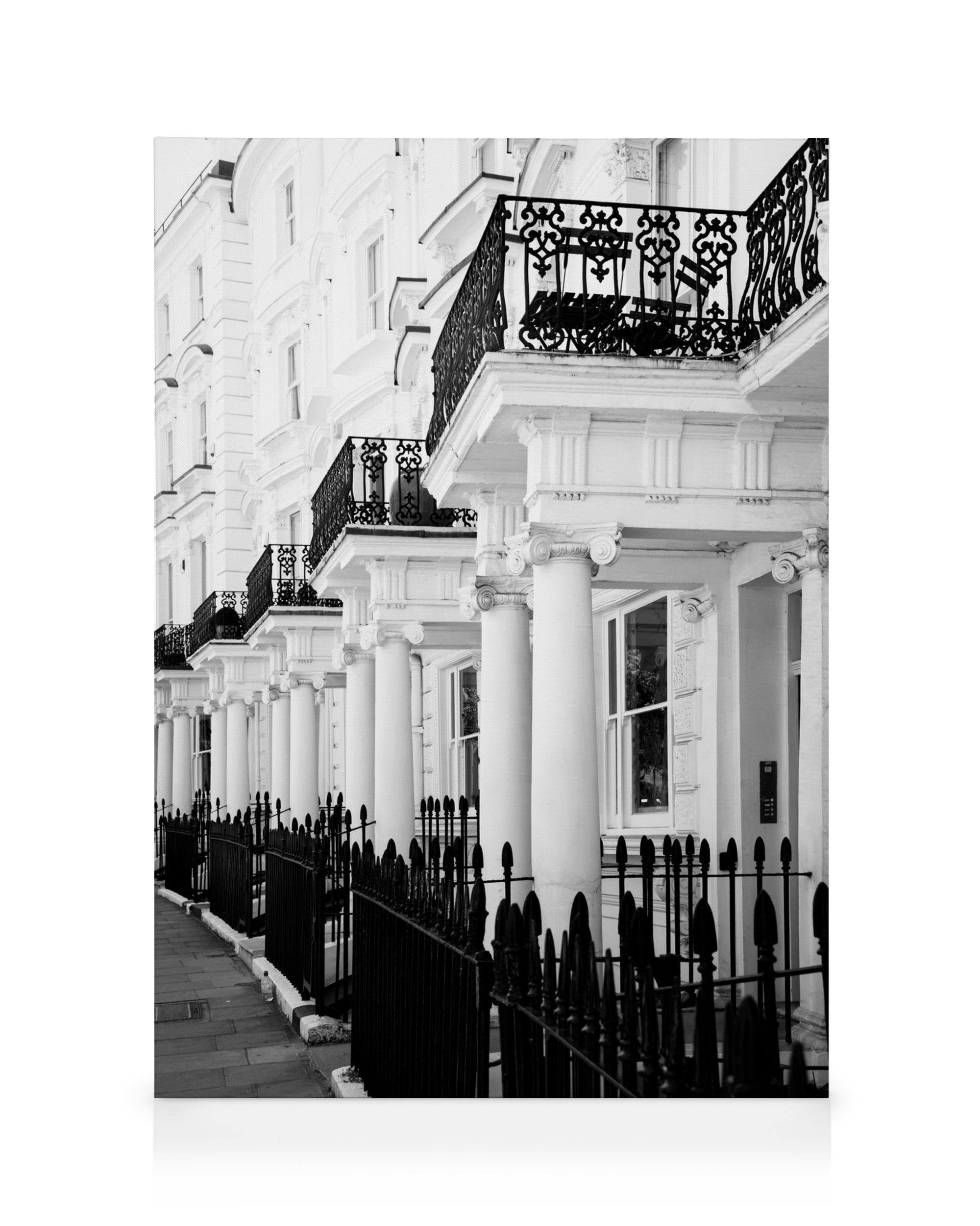 Black and white photograph of Notting Hill houses with white columns, black ornate balconies, and iron fences, London street sce