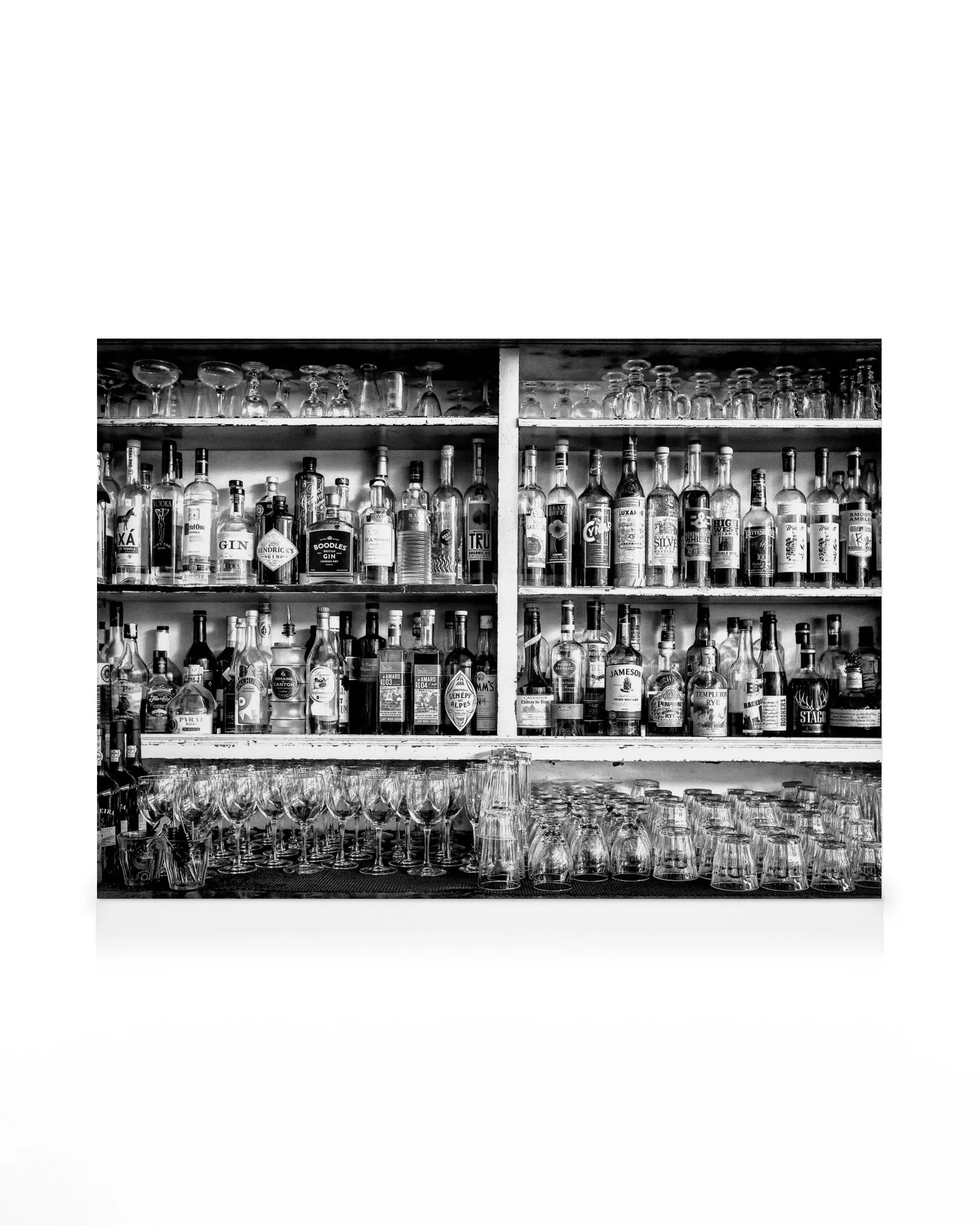 Černobílé plátno s lahvemi a sklenicemi na policích baru.