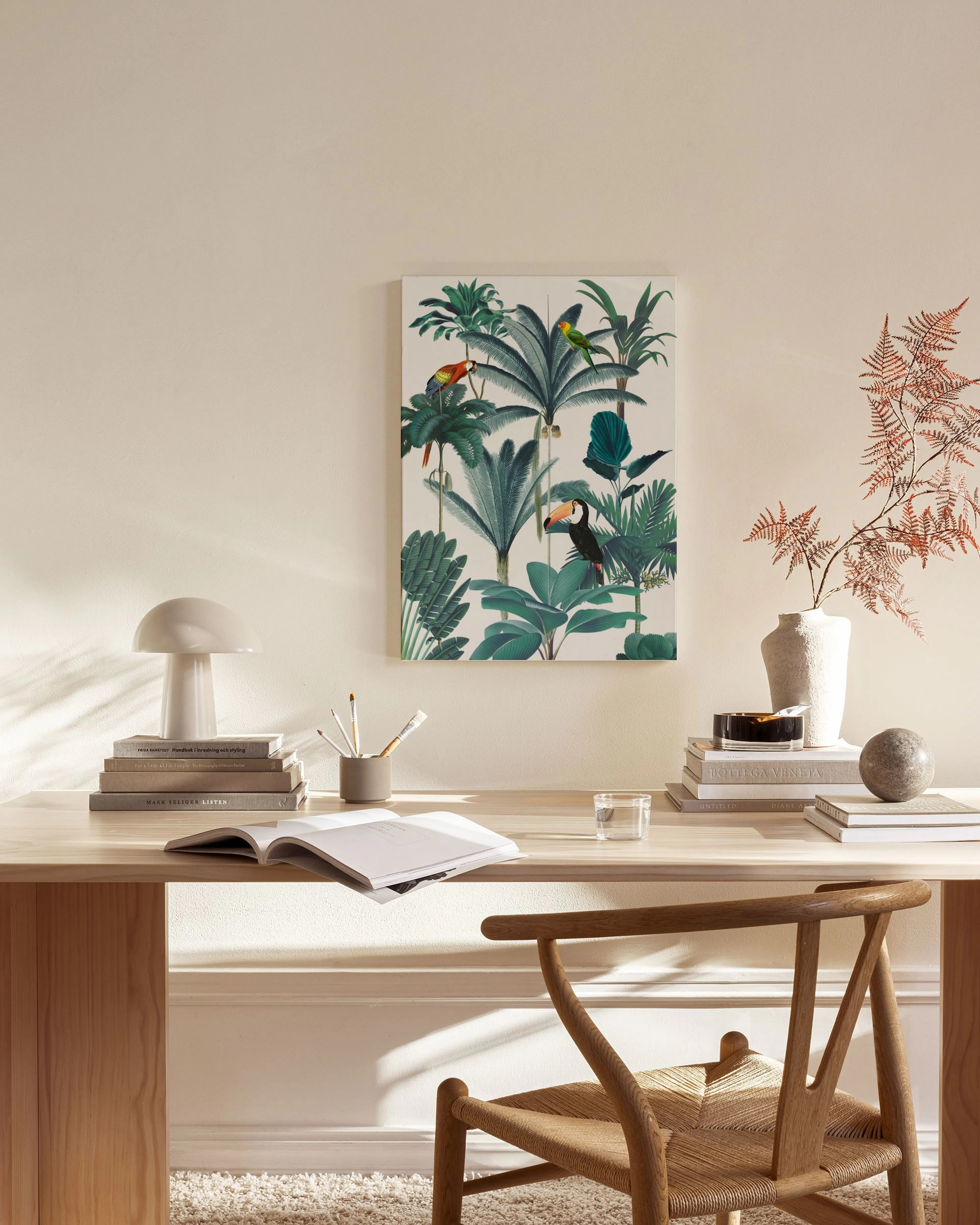 Tropical jungle canvas print with green palm leaves, colourful parrots, and a toucan, displayed in a light-filled living room.