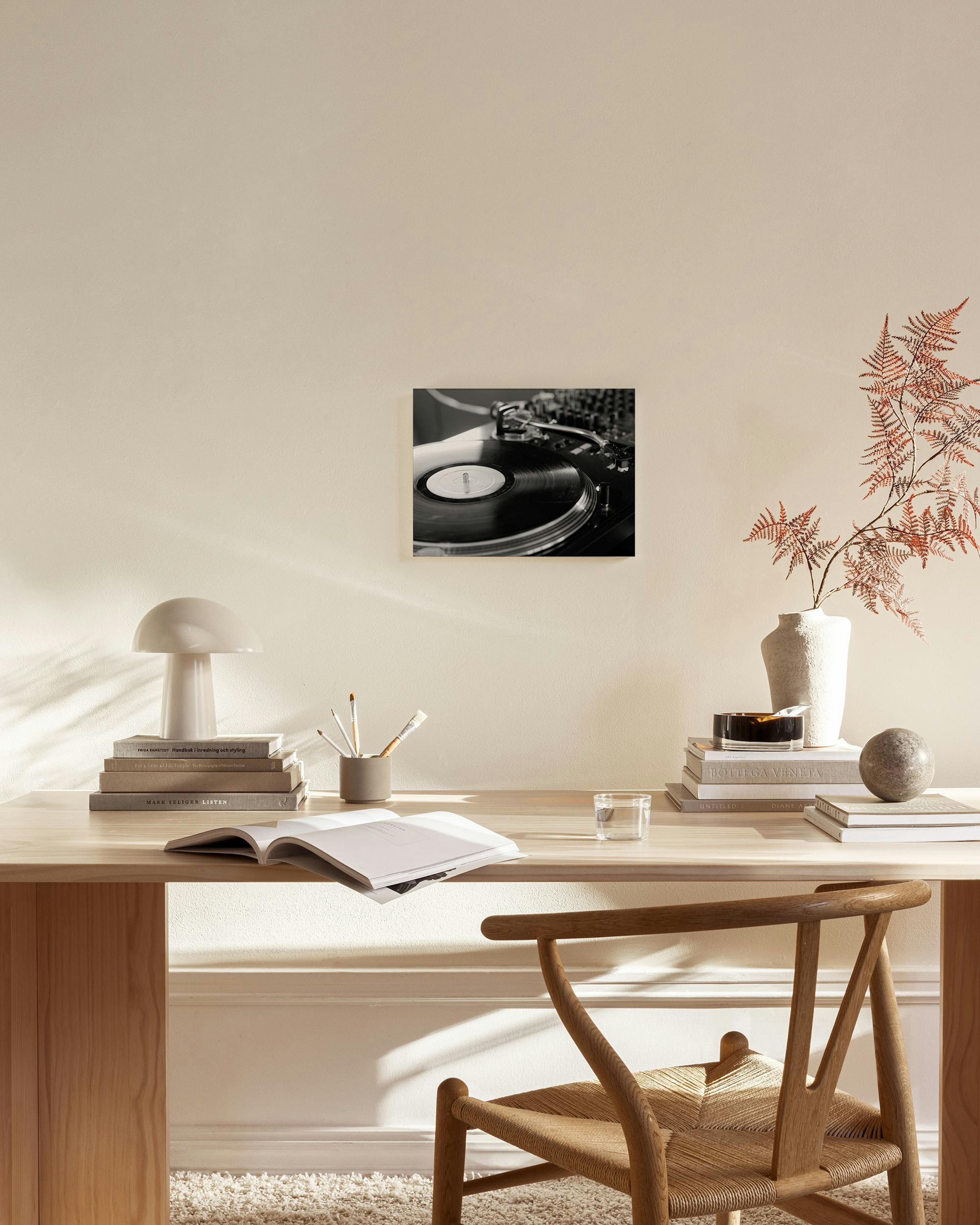 A black and white canvas print of a turntable with a vinyl record, displayed in a modern living room above a wooden console.