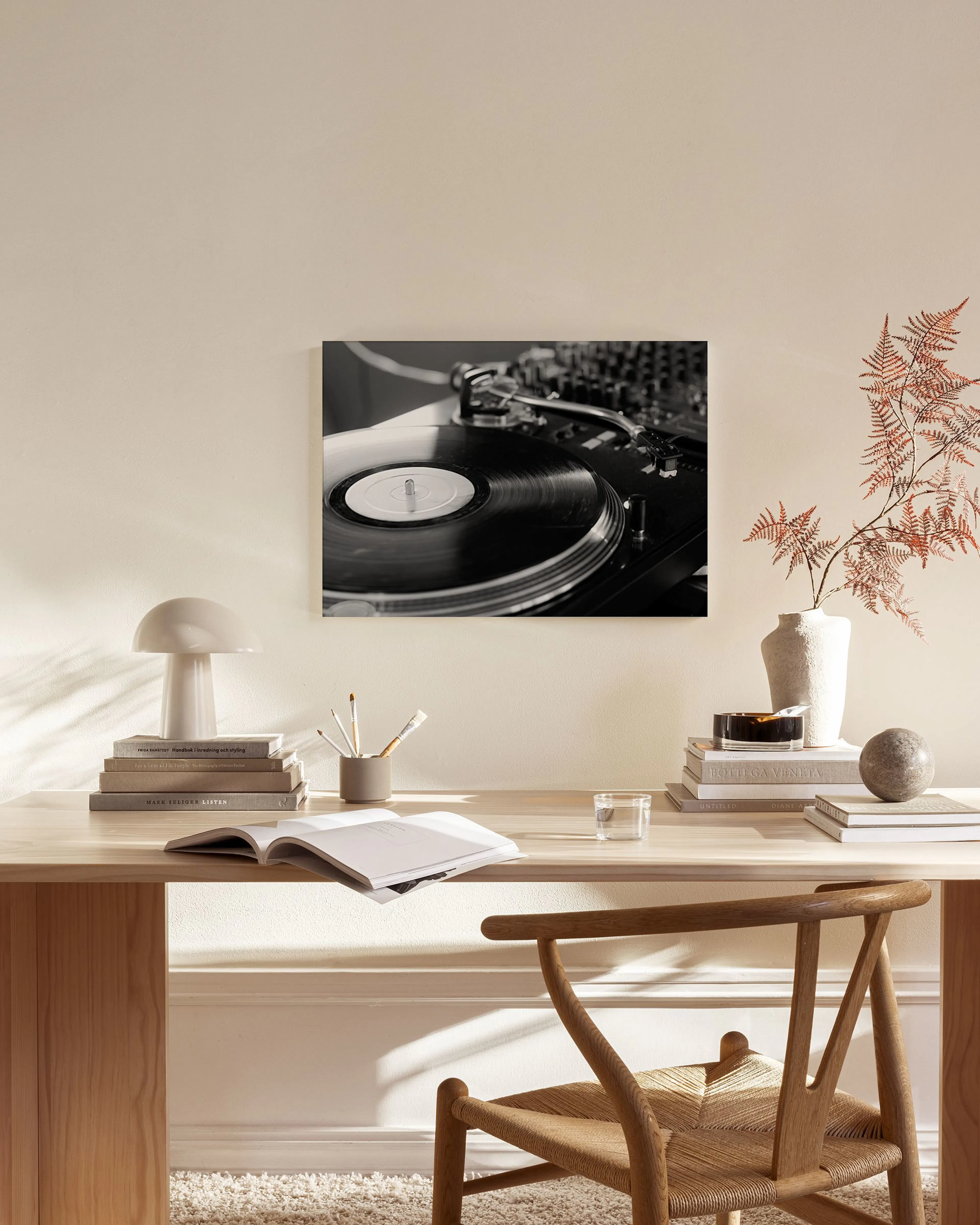Toile noir et blanc dune platine vinyle, affichée dans un salon moderne avec un fauteuil en bois et une table basse en verre.