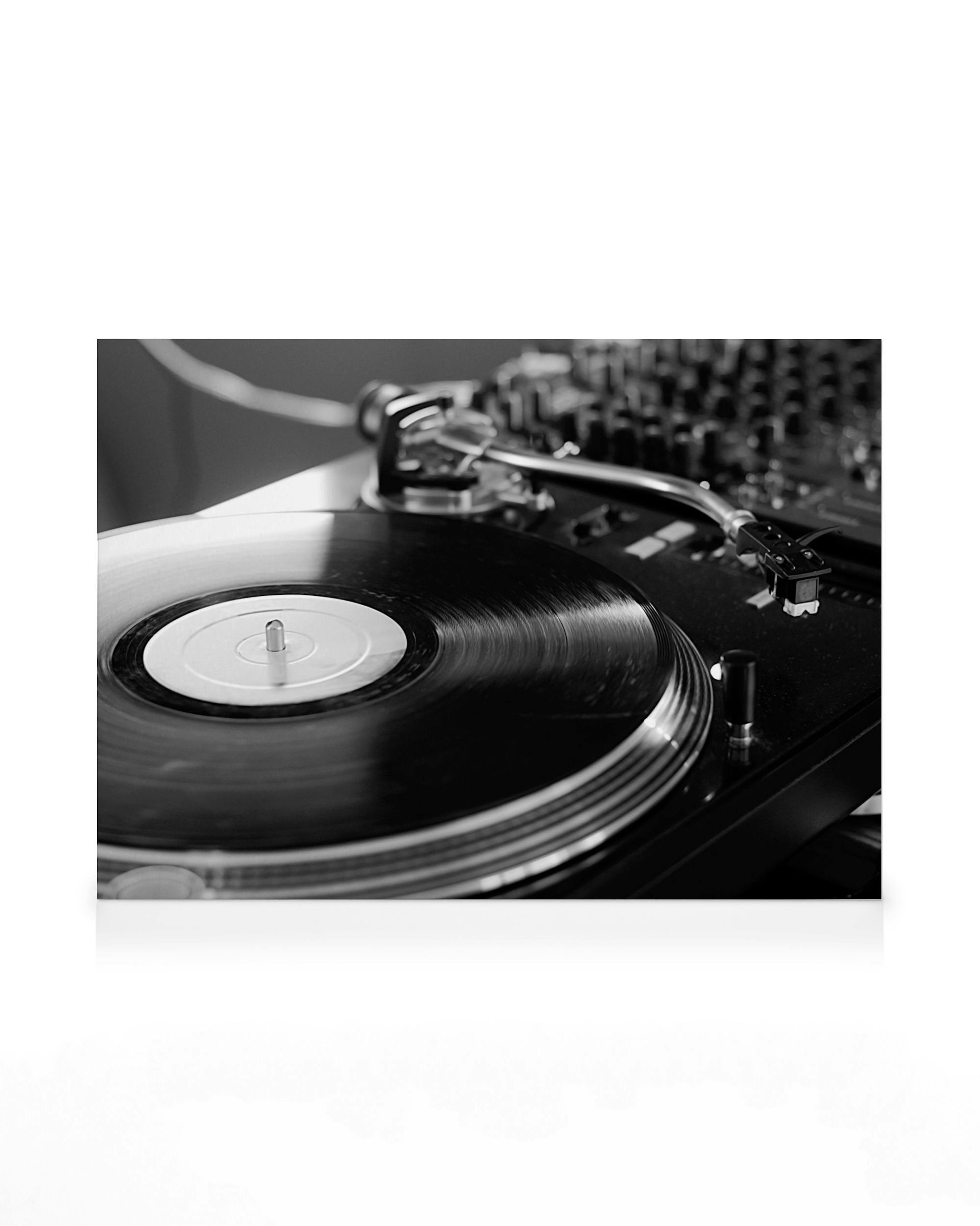 Black and white close-up of a turntable with a vinyl record, showcasing a classic DJ setup and analog music.