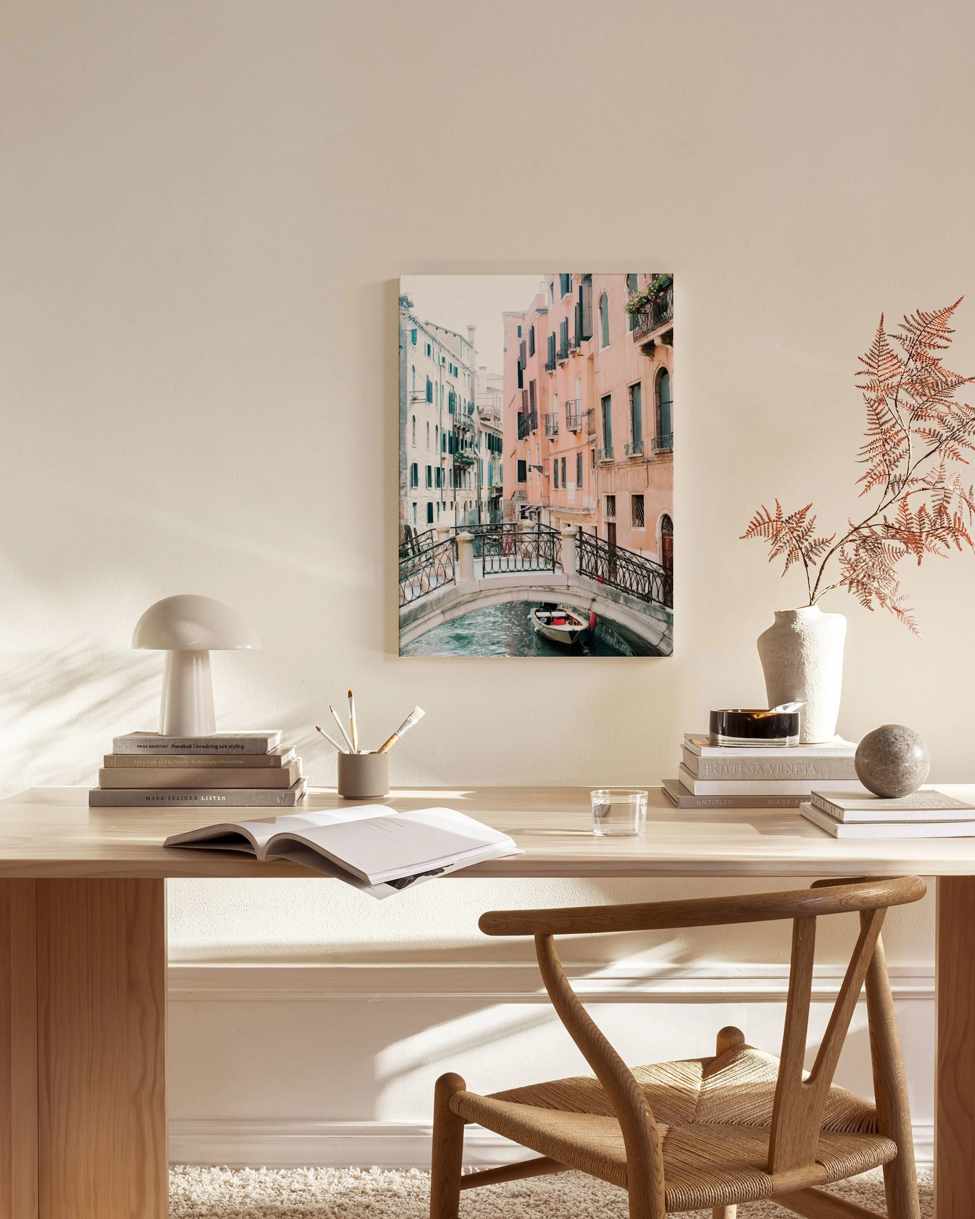 Et lærred af en bro over en kanal i Venedig med pastelfarvede bygninger og en lille båd.