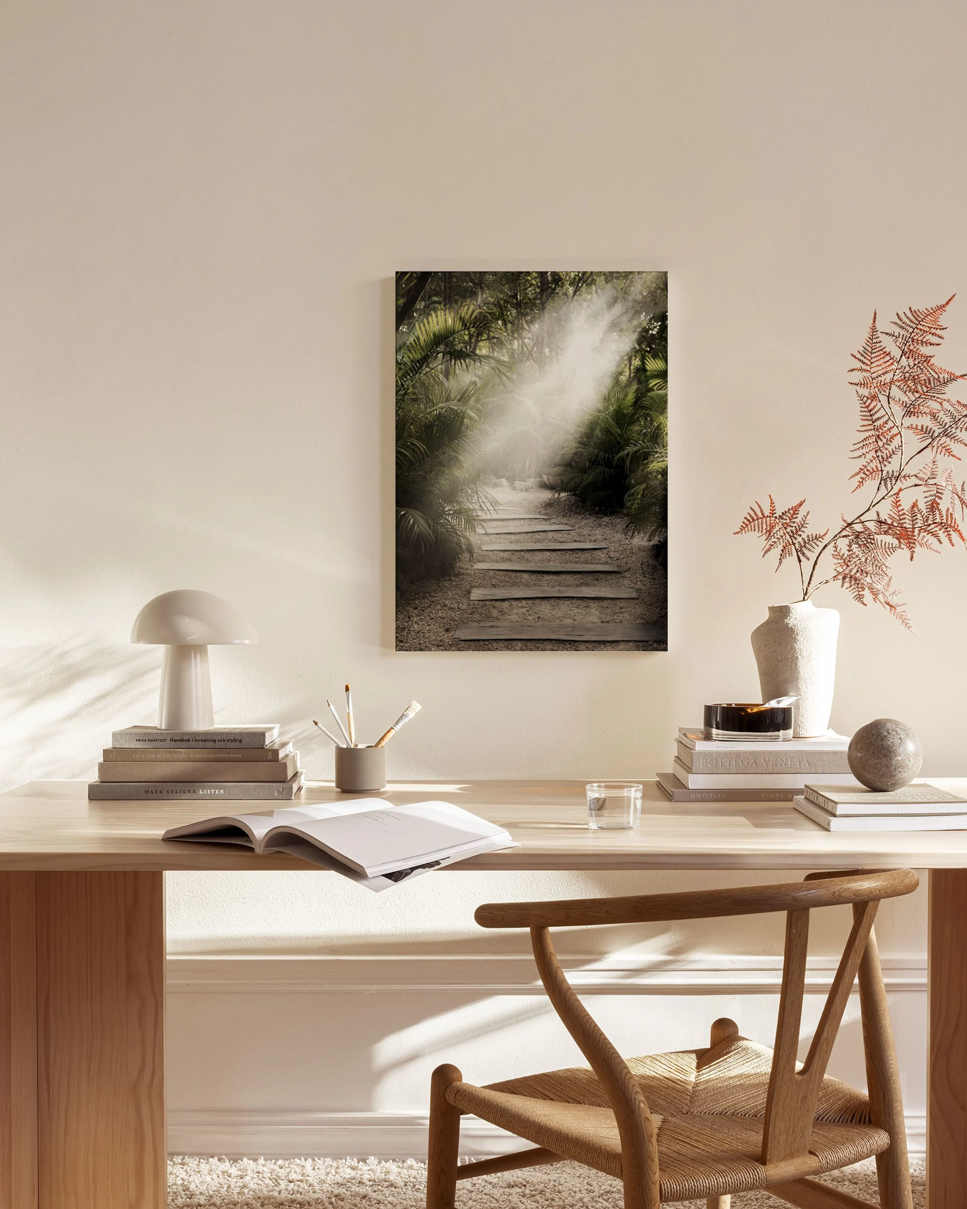 A canvas print of a sunlit jungle path with stone steps, displayed in a bright living room with neutral furniture.