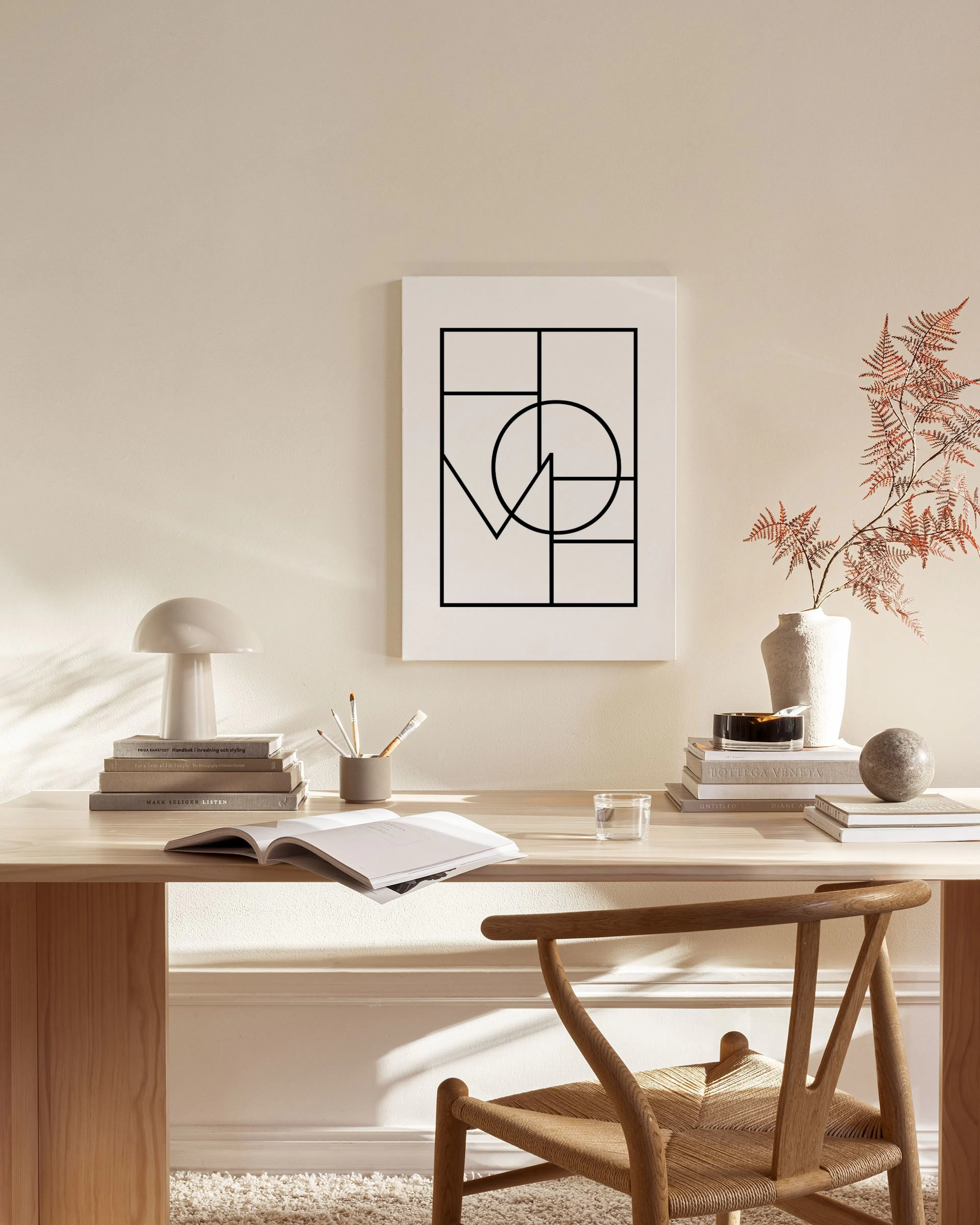 A canvas print with a black geometric LOVE design, hanging above a wooden console table in a minimalist living room.