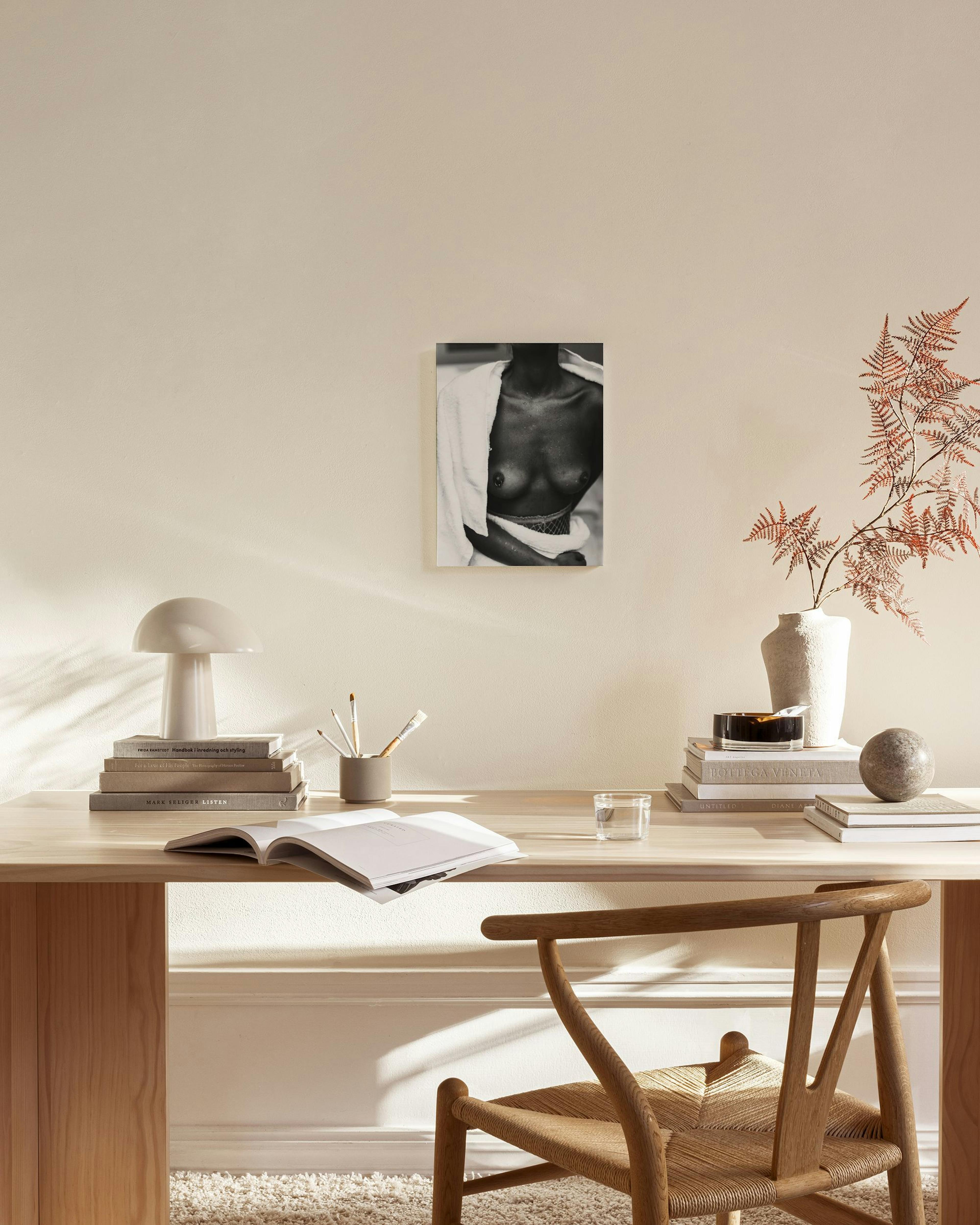 Zwart-wit canvas van een vrouw met ontbloot bovenlichaam en een witte handdoek, hangend in een neutrale woonkamer.