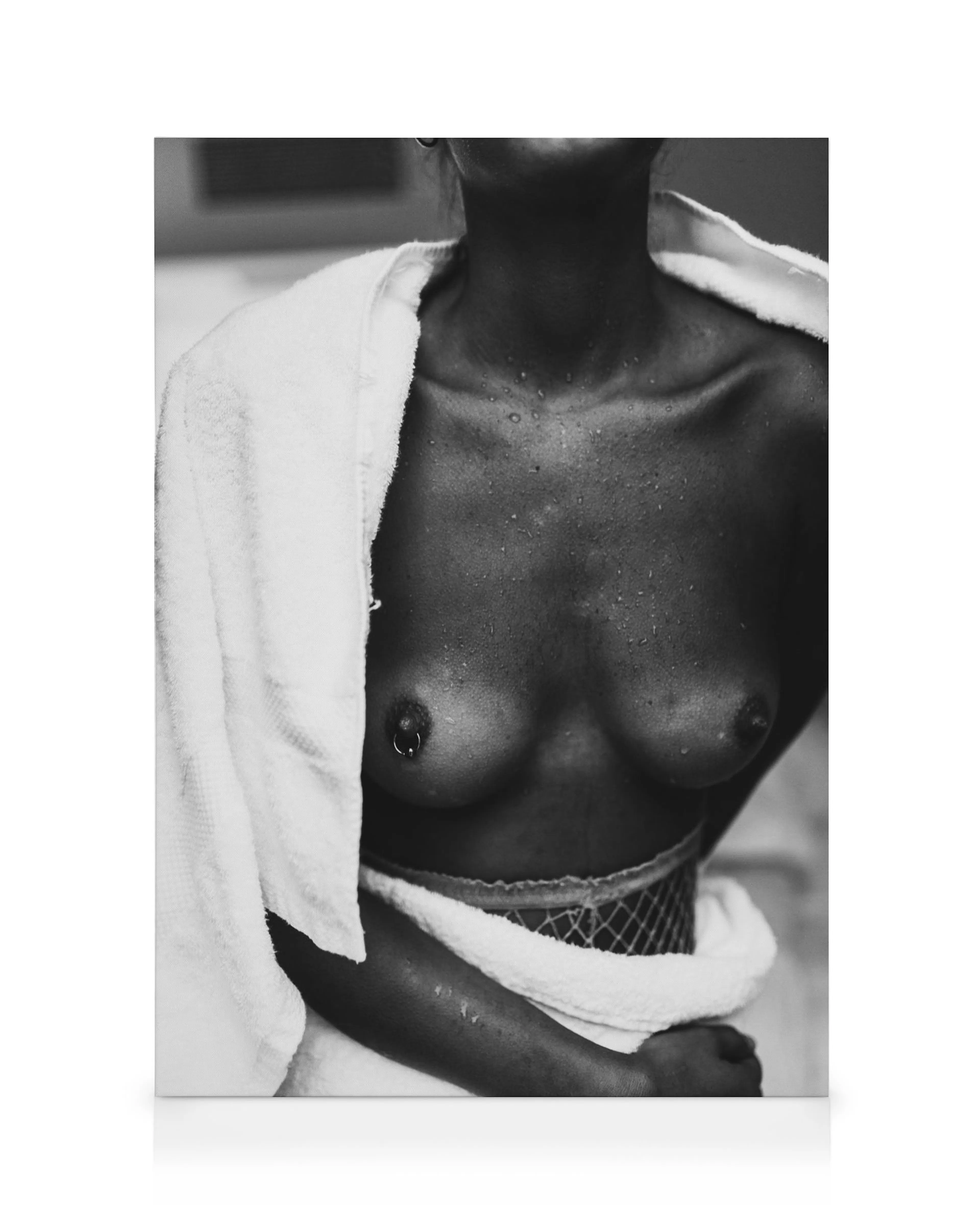 Black and white canvas print of a person with dark skin, water droplets, and a towel draped over their shoulders. One nipple is 