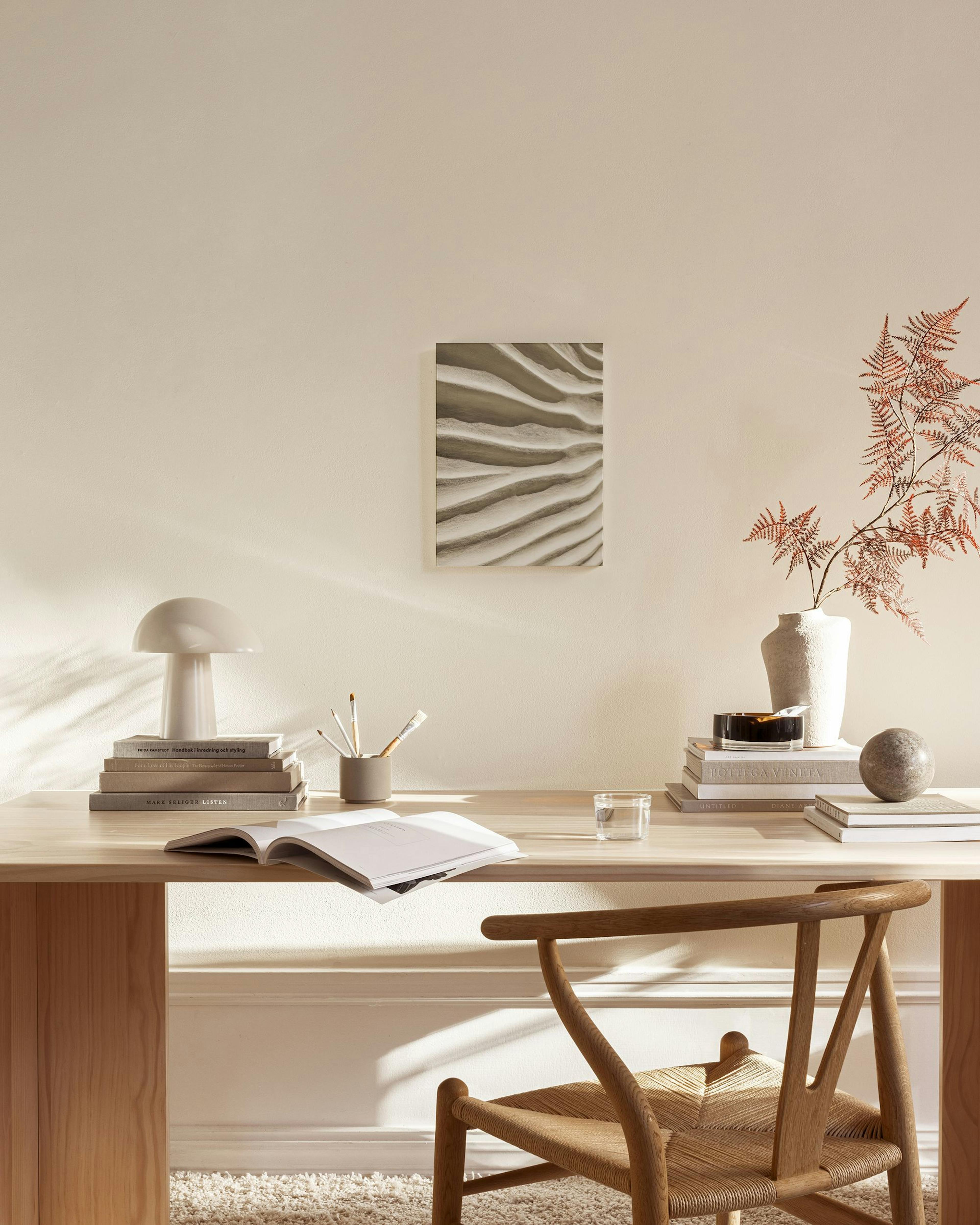 Leinwandbild mit Wellenmuster in Sandtönen, über einem Sideboard in einem hellen Wohnzimmer.