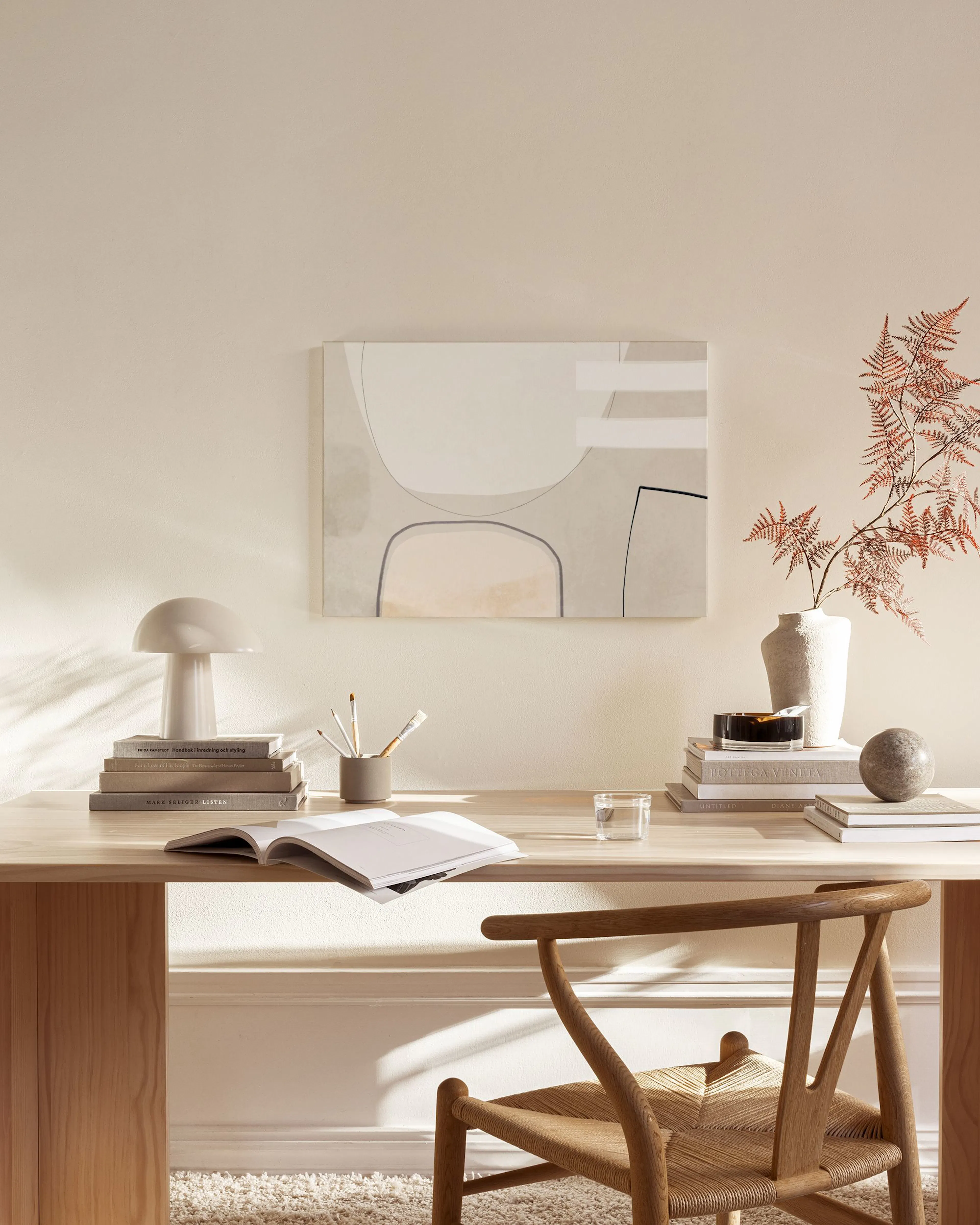 Abstract canvas print with organic shapes in beige and grey tones, hanging in a minimalist living room.