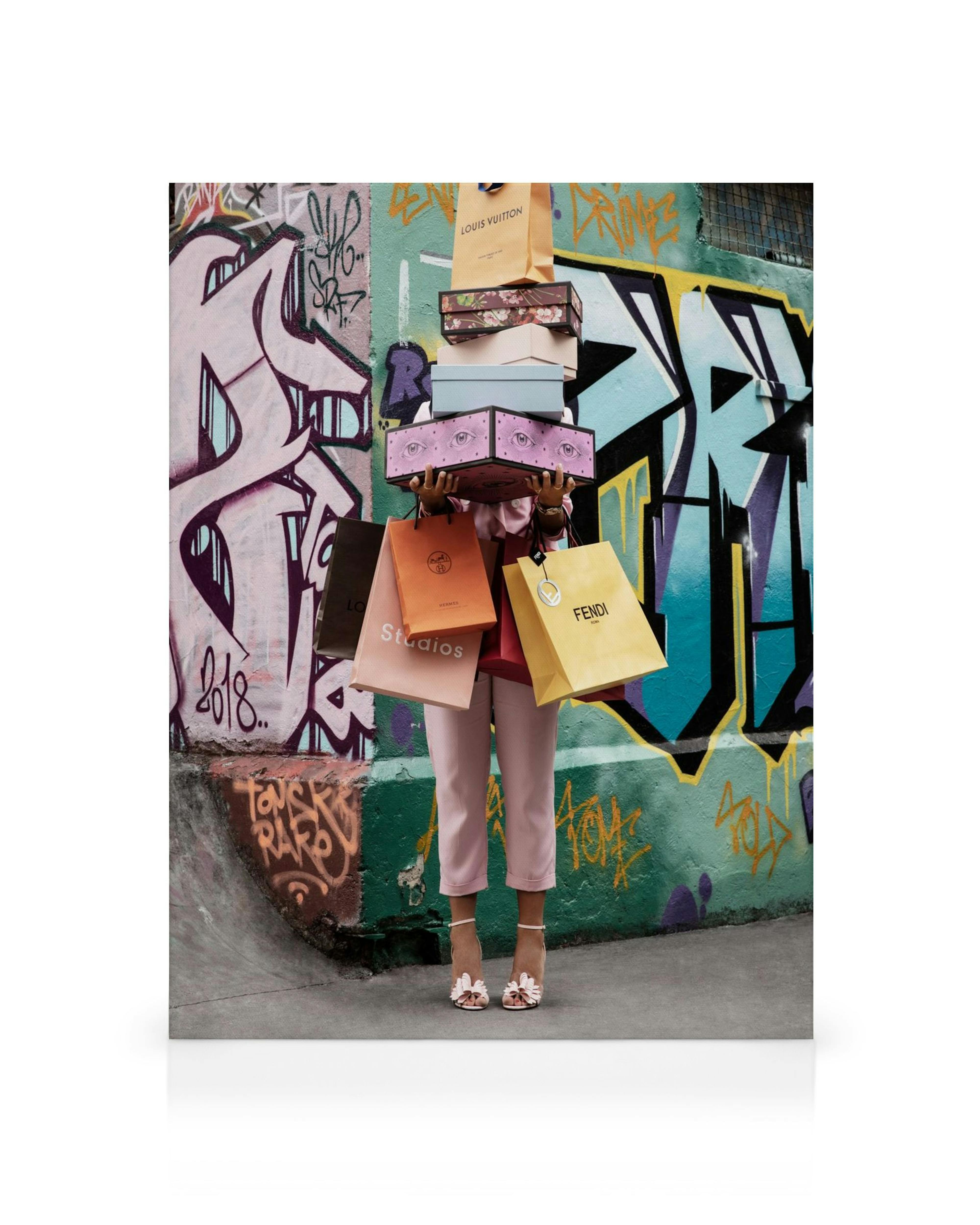 Leinwandbild mit Person, die Einkaufstüten und Boxen vor graffitibewachsener Wand hält, Lifestyle-Deko