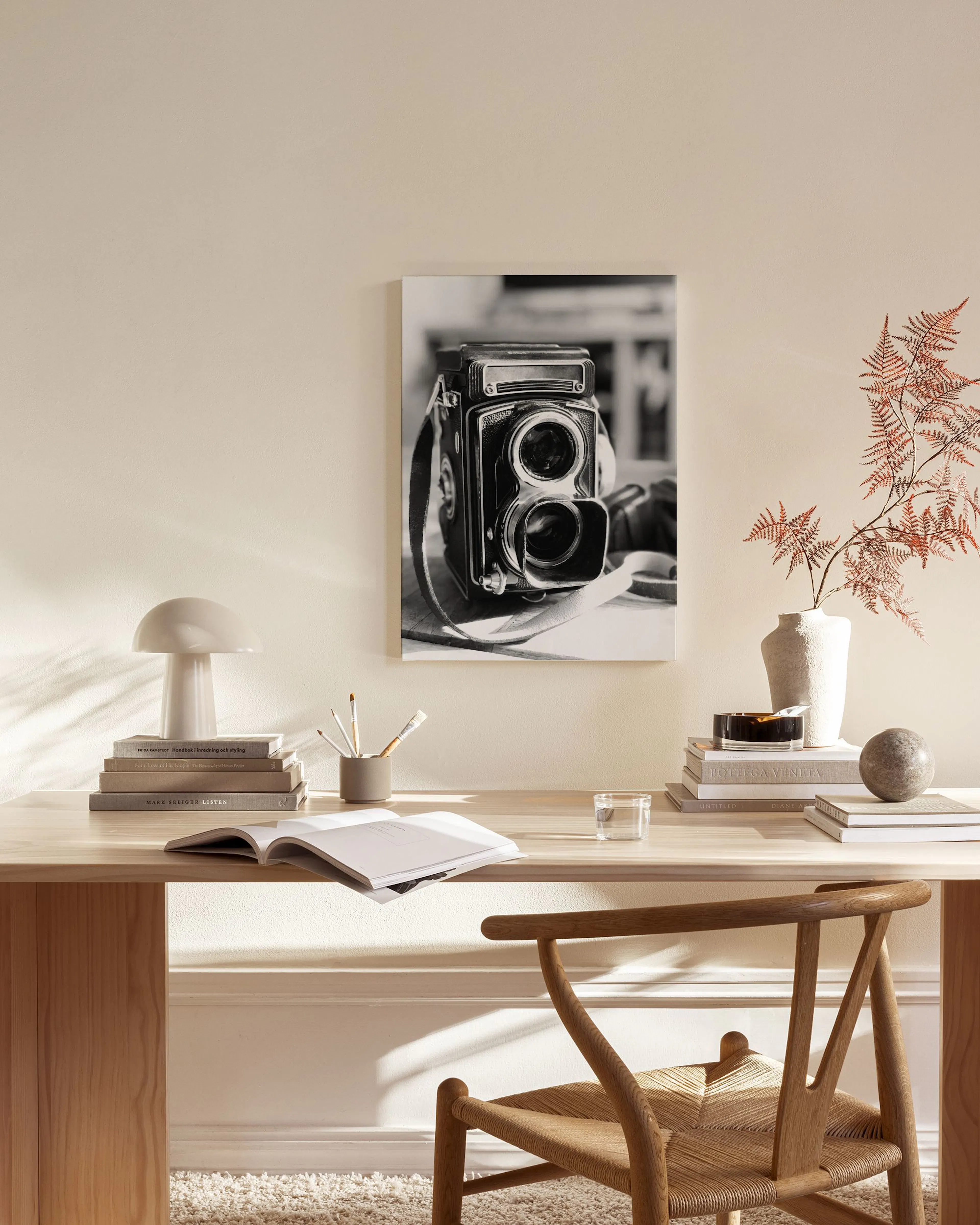 A black and white canvas print of a vintage twin-lens reflex camera hangs in a minimalist living room.