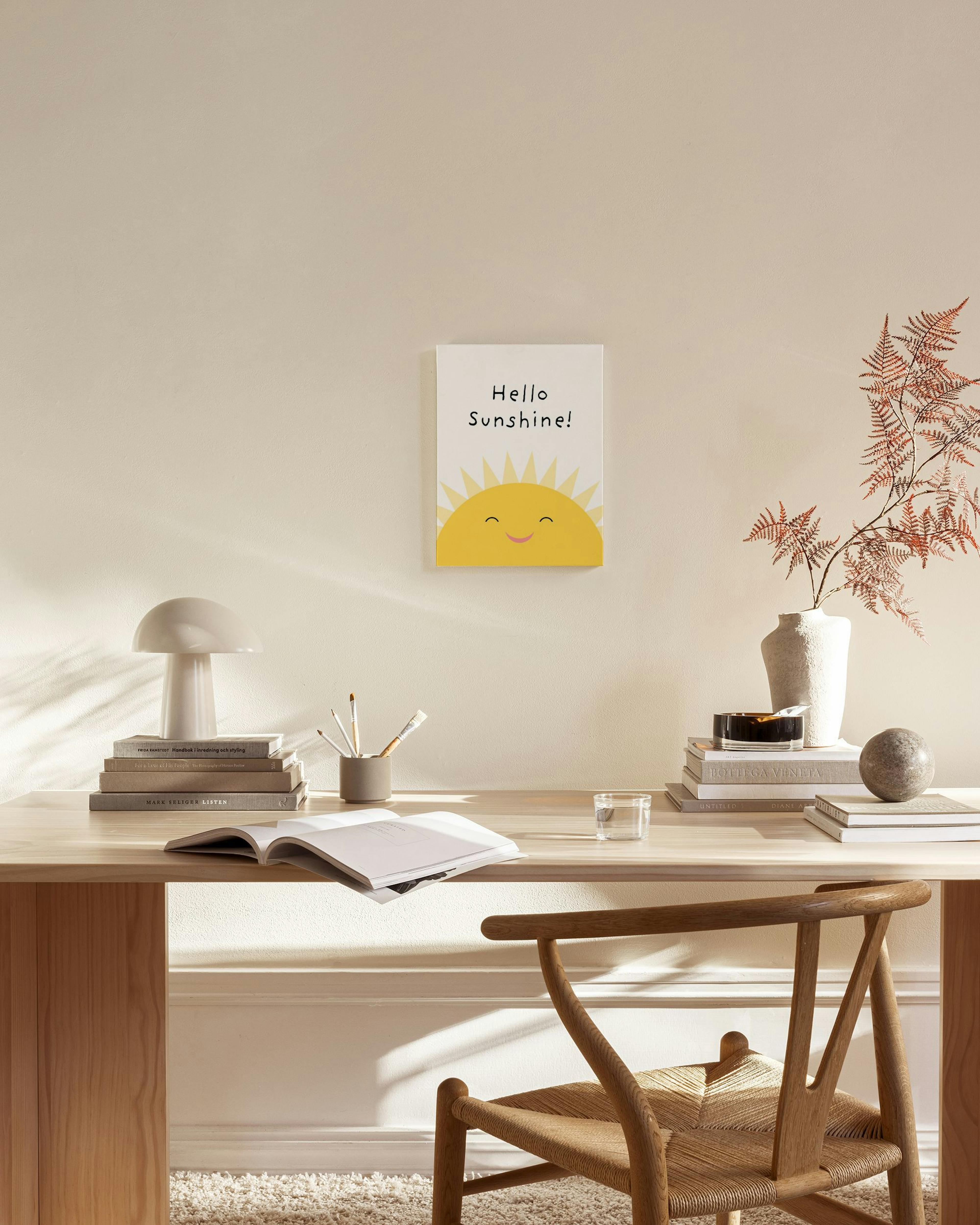 Leinwandbild mit einem lachenden Sonnenmotiv und dem Text Hello Sunshine!“ in einem modernen Wohnzimmer.