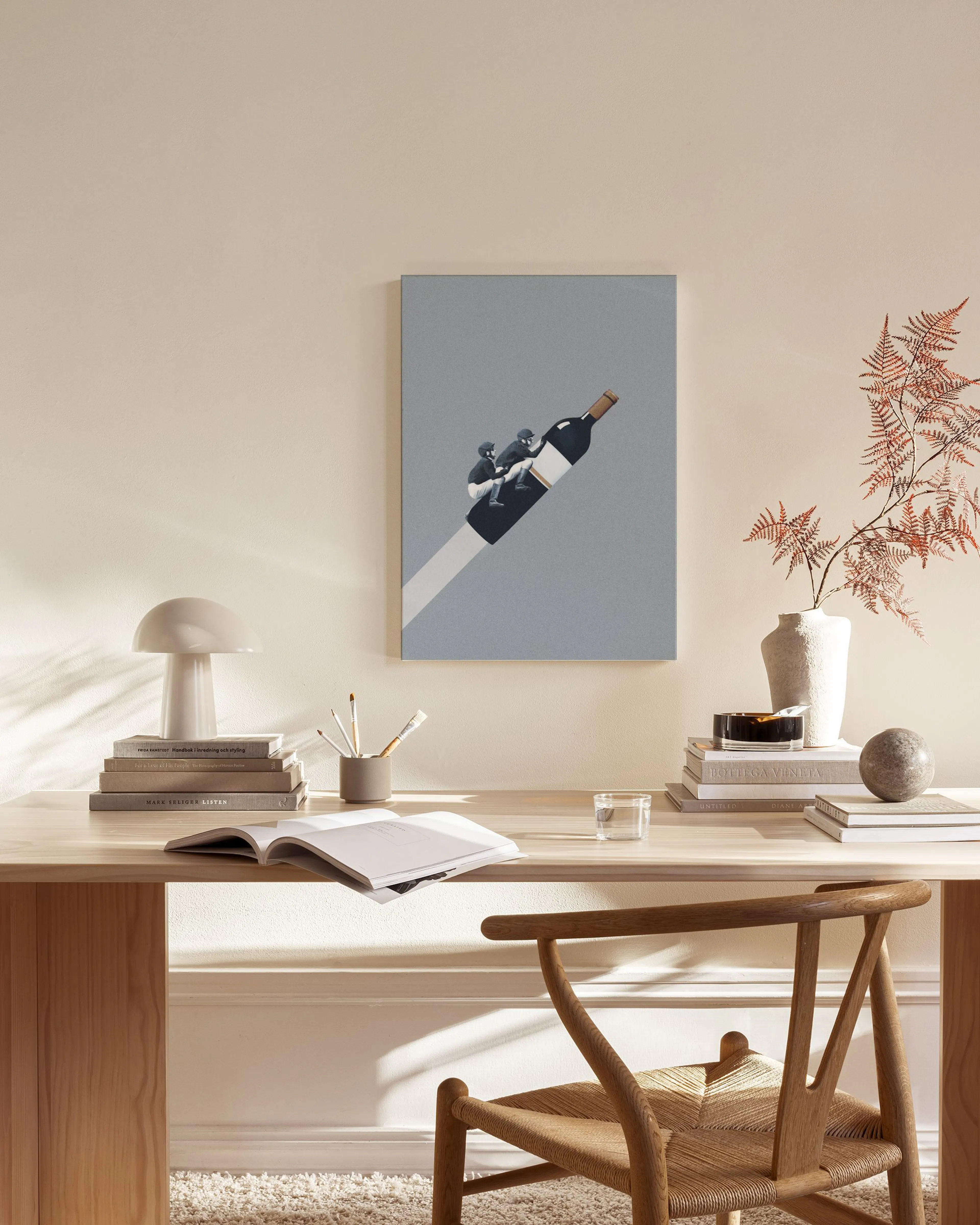 Humorous canvas print of two people riding a flying wine bottle against a grey background, displayed in a minimal living room.