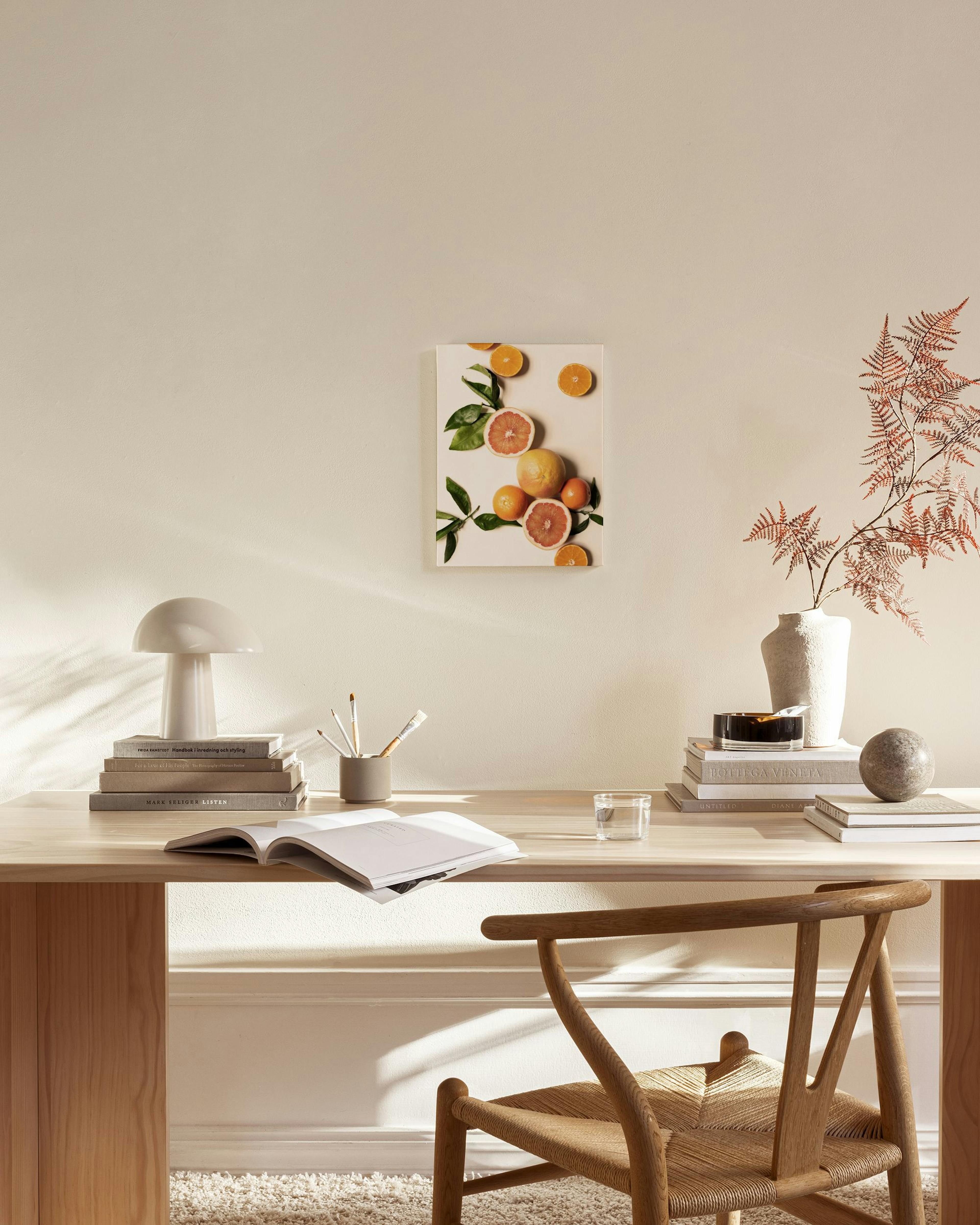 A canvas print of sliced and whole grapefruits and oranges with green leaves, displayed on a light wall in a modern living room.