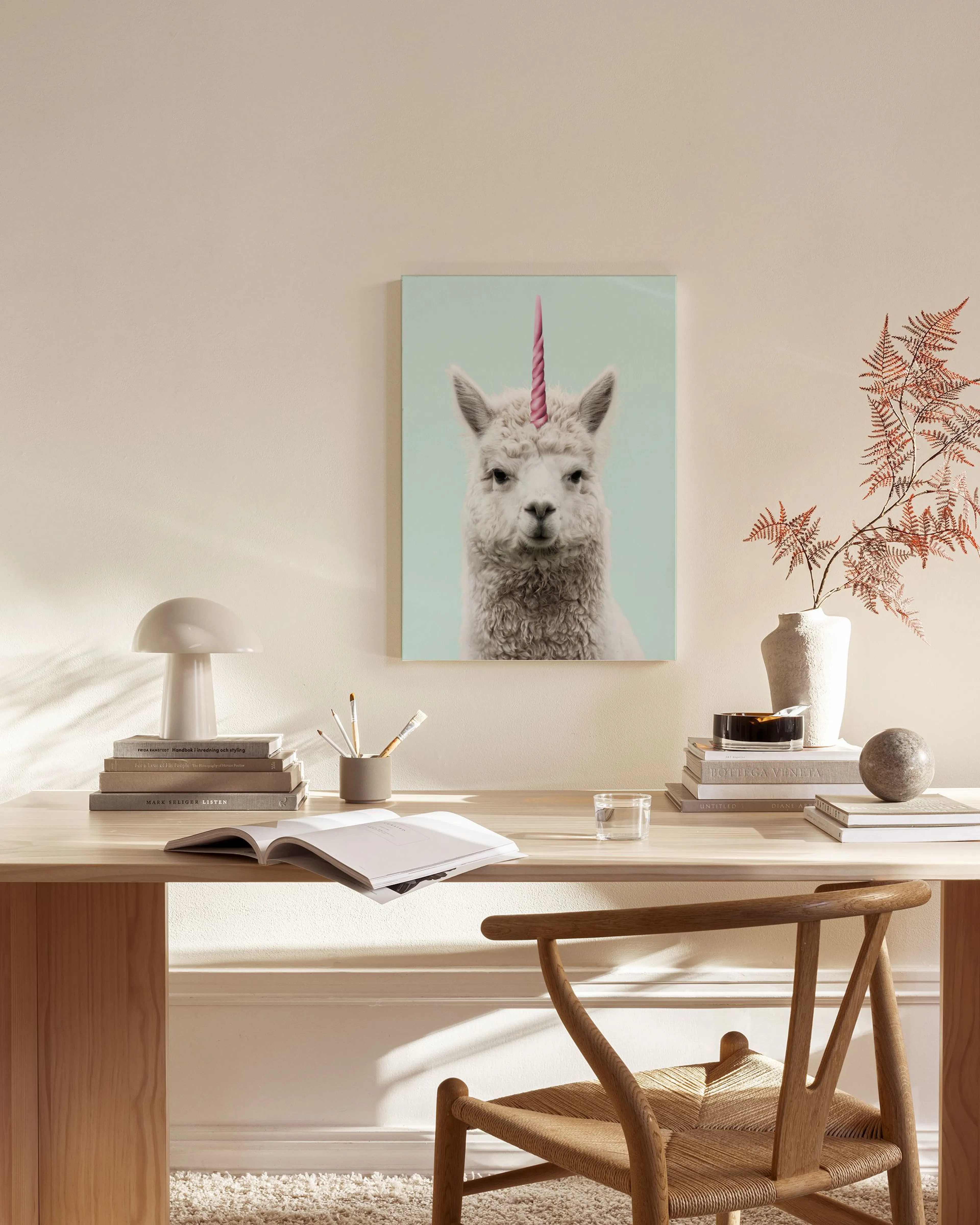 Leinwandbild mit einem weißen Alpaka und einem rosa Einhorn-Horn vor hellblauem Hintergrund.
