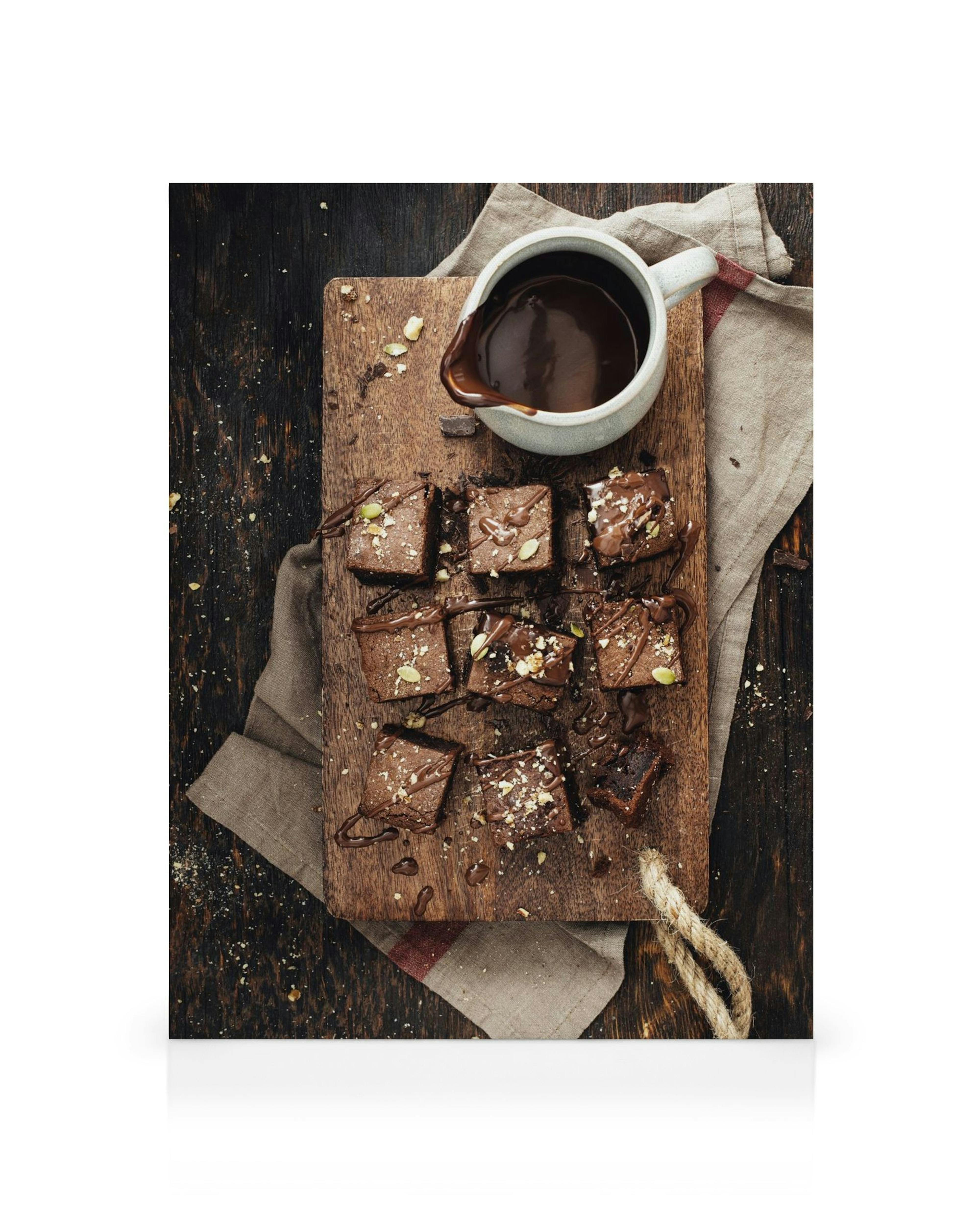 Chocolate brownies on a wooden board with chocolate sauce and nuts, a delicious canvas print for your kitchen.