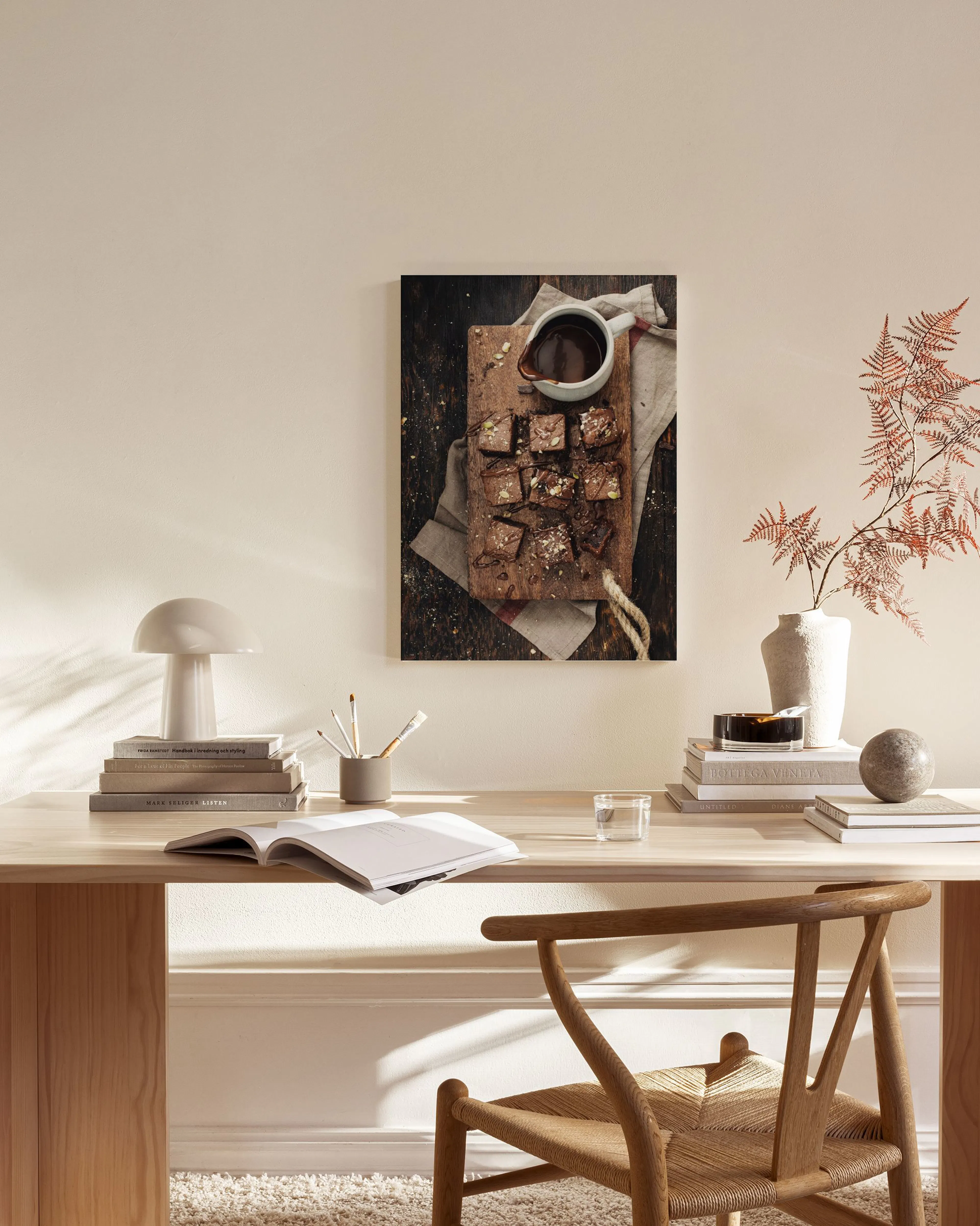 Toile de brownies au chocolat avec une tasse de sauce sur une planche en bois, accrochée dans un salon scandinave clair.