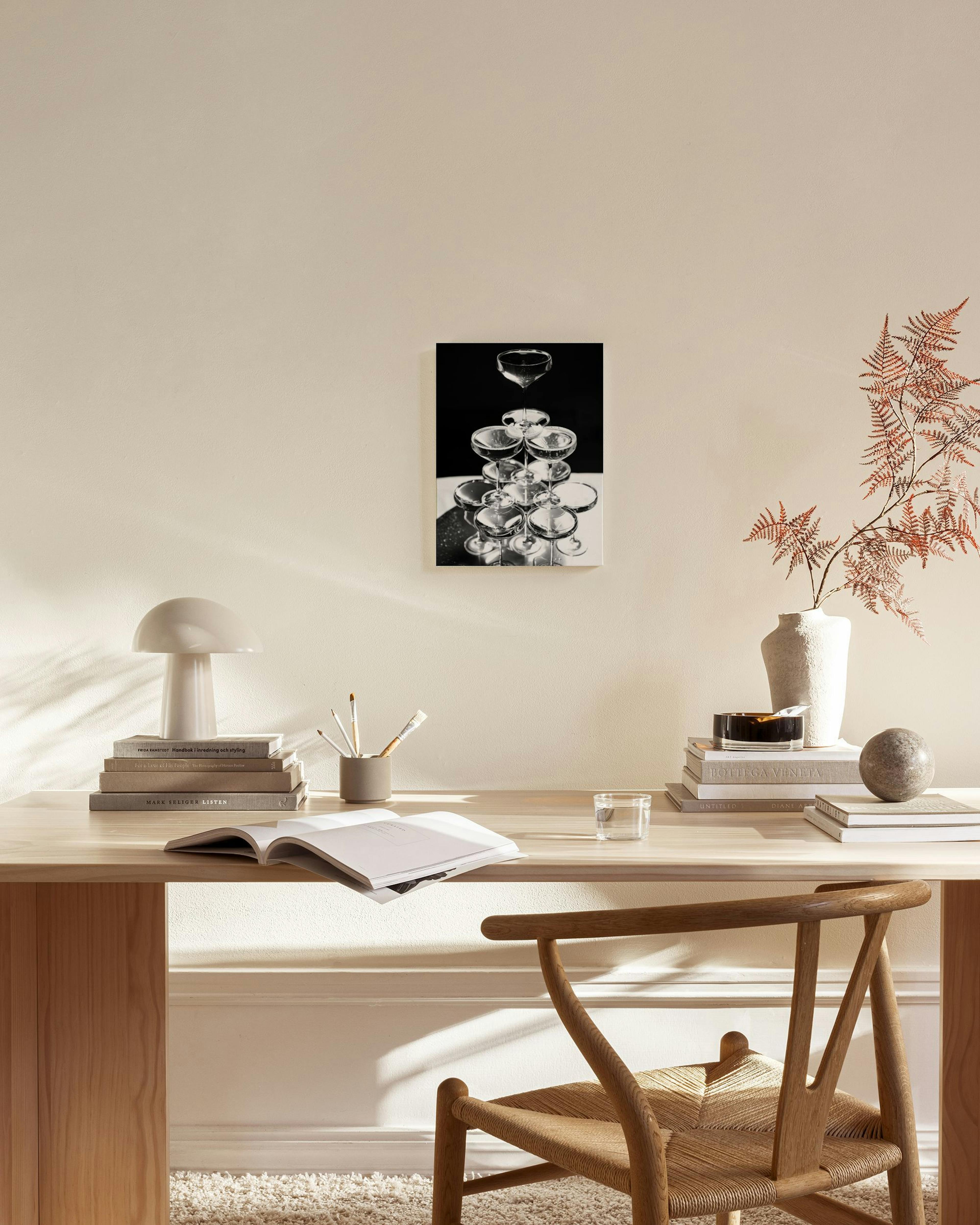 Toile noir et blanc dune pyramide de coupes de champagne, accrochée dans un salon moderne et lumineux.