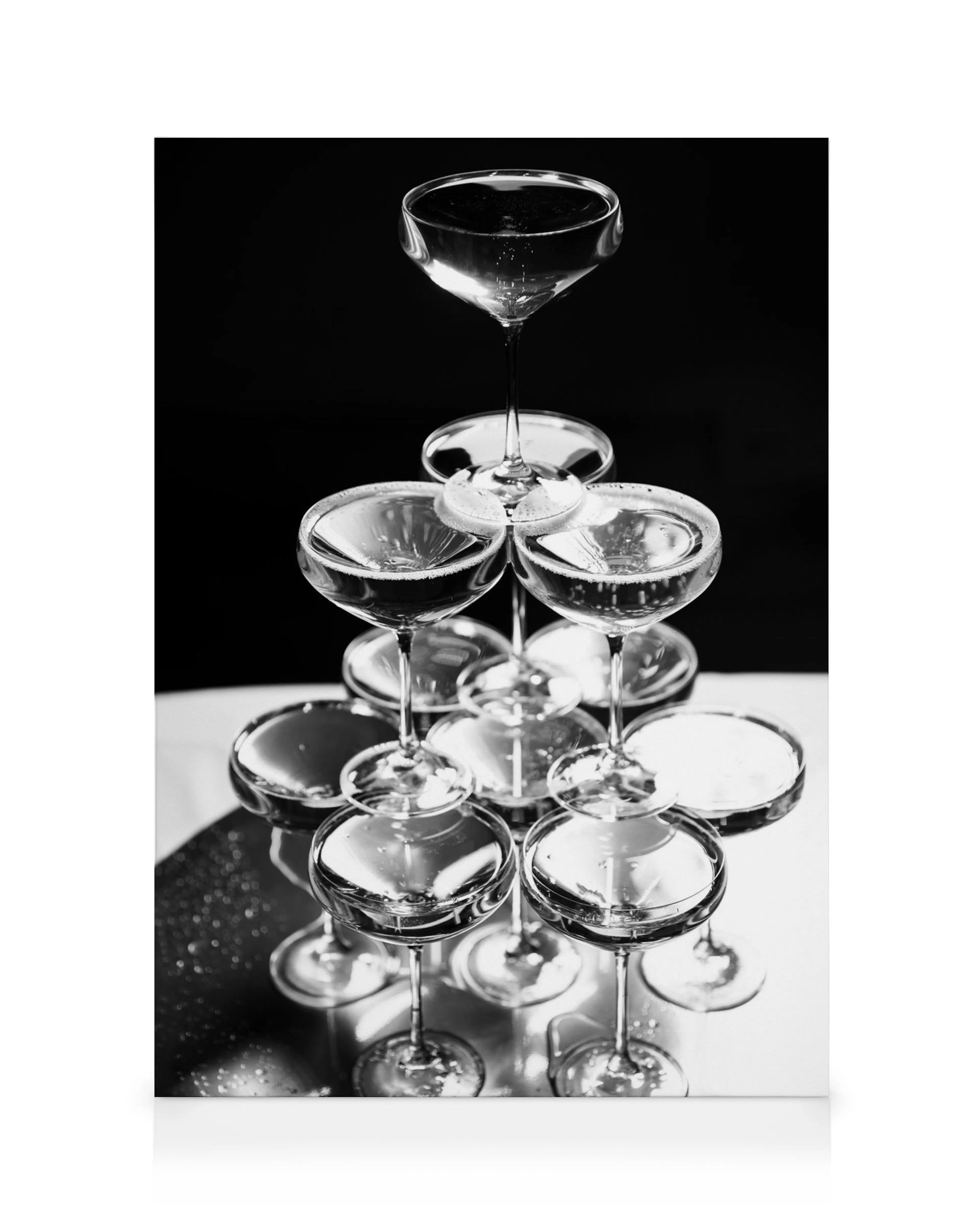 Svart-hvitt fotografi av et elegant pyramidetårn av stablede champagneglass med reflekterende overflater, fylt med glitrende bob