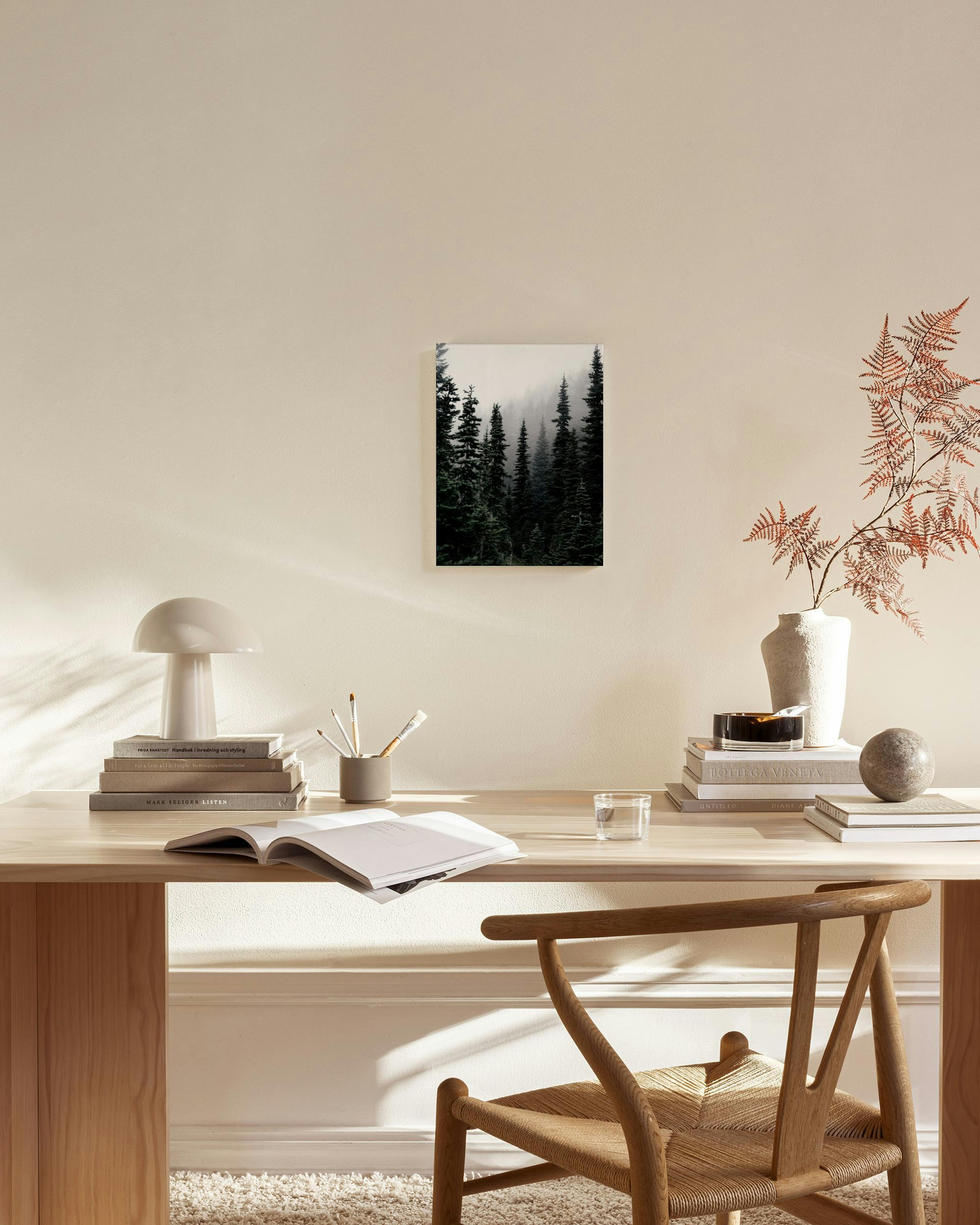 Toile murale forêt brumeuse, tons vert foncé, accrochée dans un salon moderne aux couleurs claires.