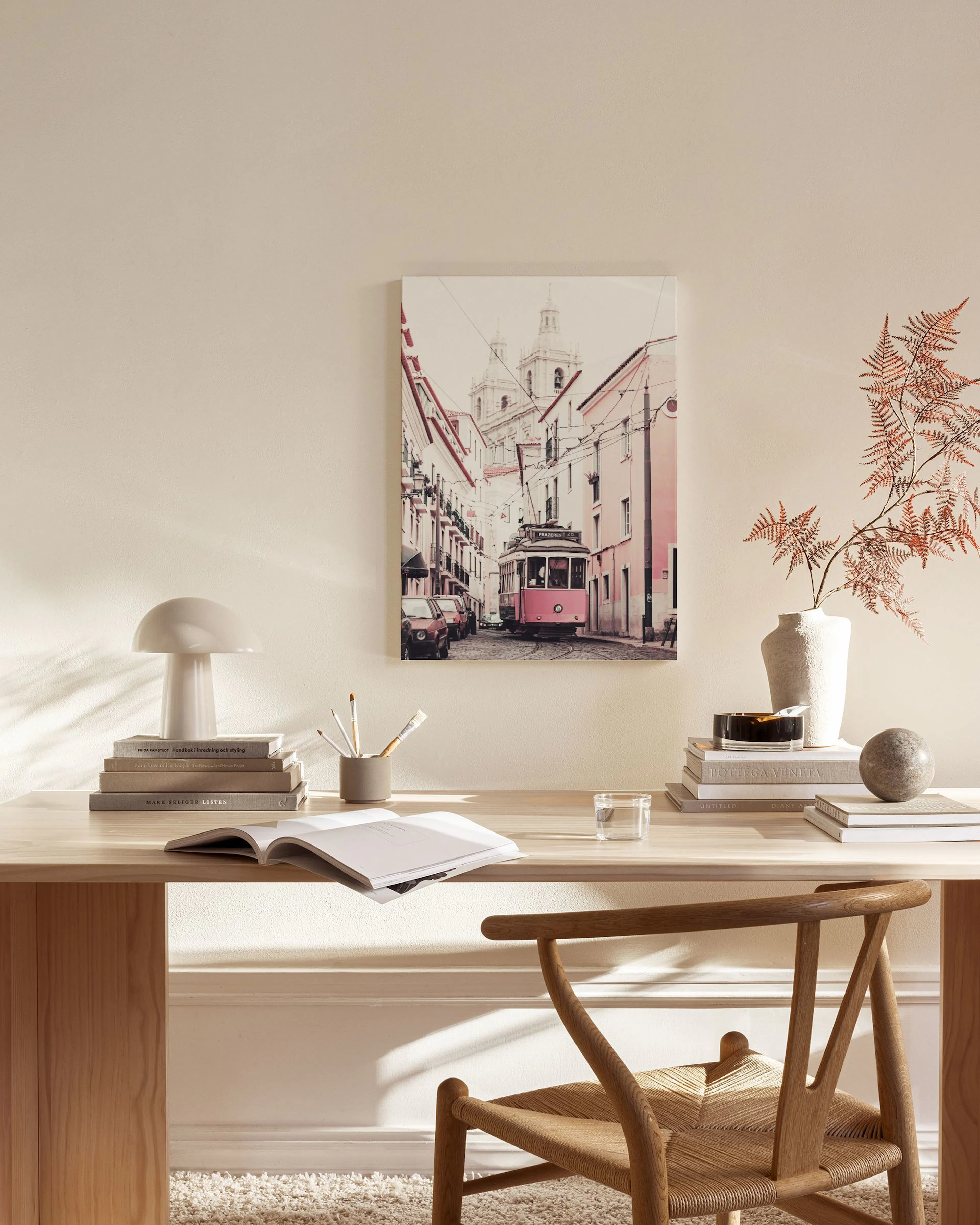 A canvas print of a pink tram in a European street, hanging in a bright living room above a light wood console table.