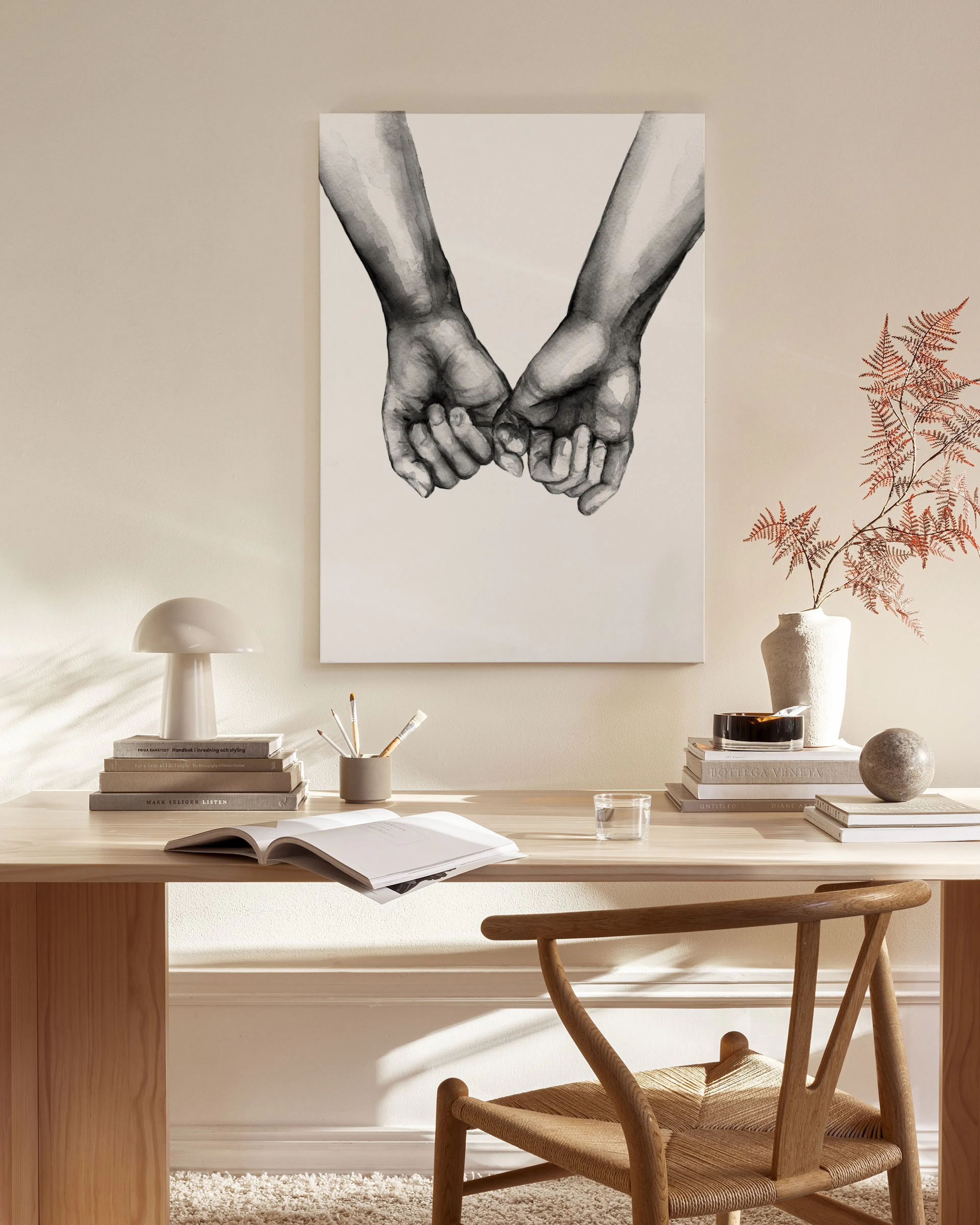 Leinwandbild mit zwei sich haltenden Händen in Schwarz-Weiß, hängend über einem Sideboard in einem beigen Wohnzimmer.