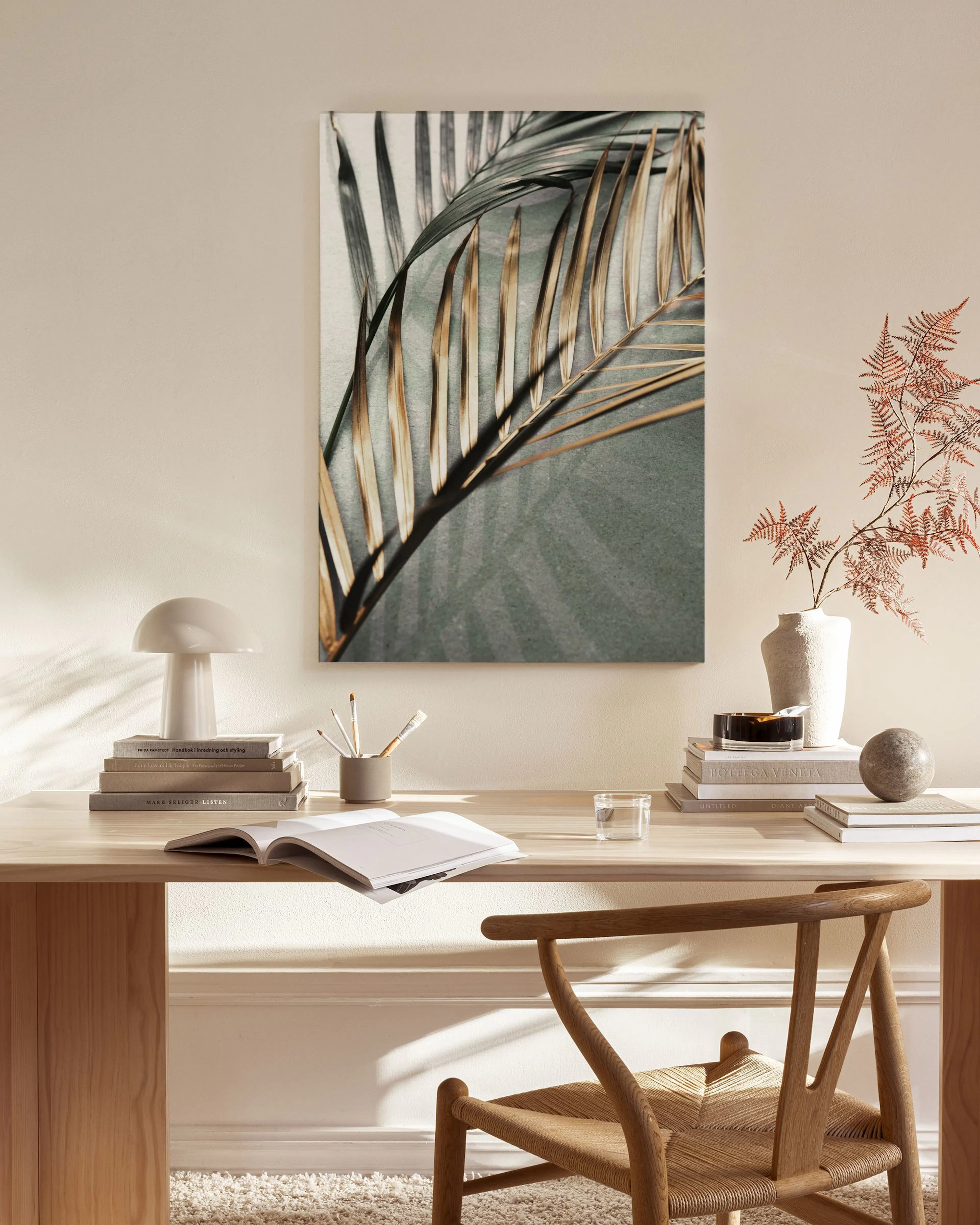 Toile murale de feuilles de palmier dorées et vertes, affichée dans un salon moderne au-dessus dune table basse en verre.