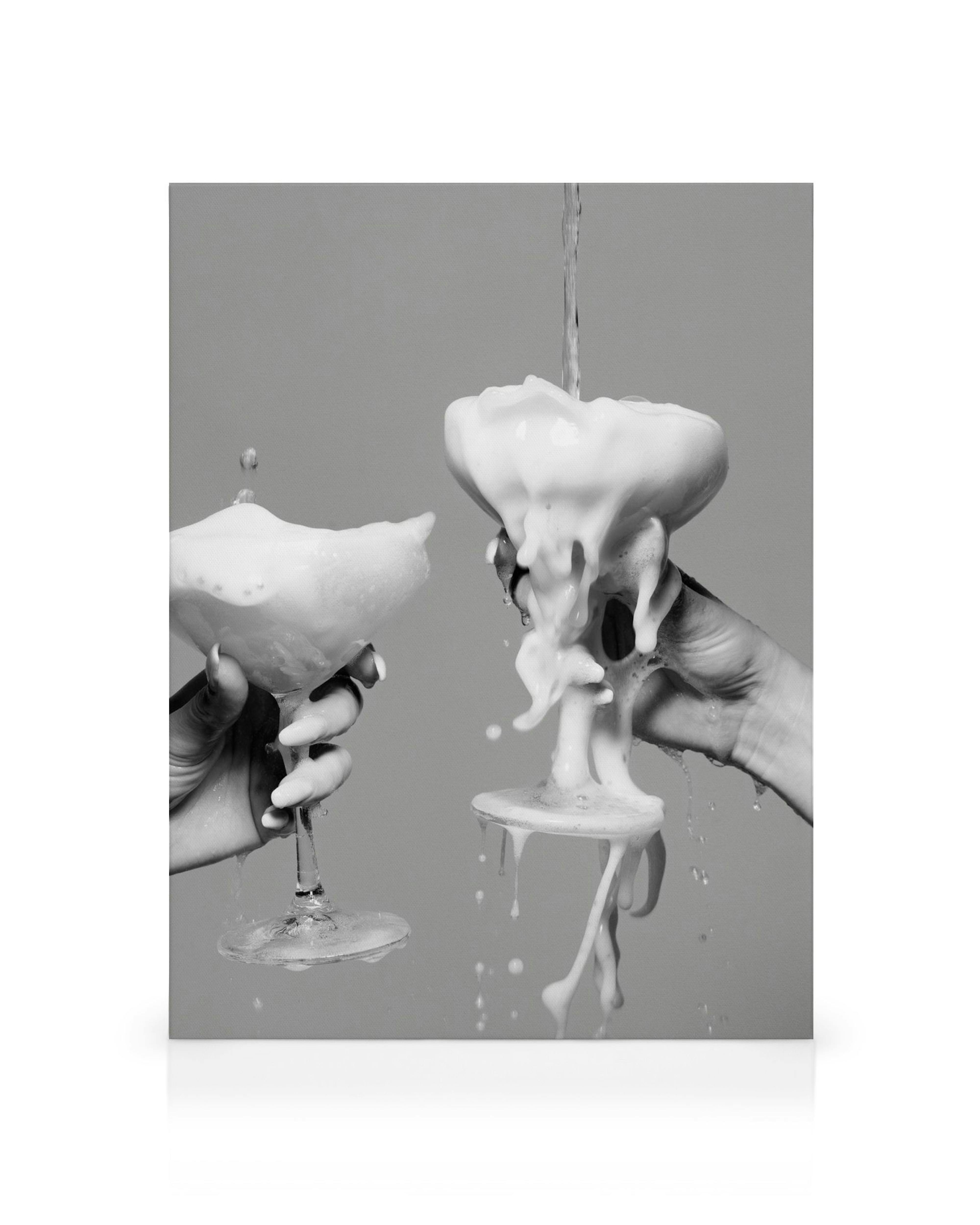 Stampa su tela in bianco e nero: due mani reggono bicchieri di champagne traboccanti di schiuma bianca che cola.